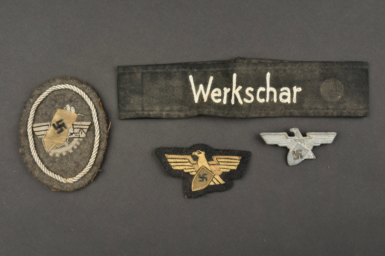 Insignes Werkschutz. Werkschutz insignia.: Insignes Werkschutz. Comprenant un brassard en tissu coton noir, broderie blanche marquee Werkschar. Un aigle de coiffure Werkschutz, en metal, attaches completes, marquages Ges Gesch. Un insigne de c