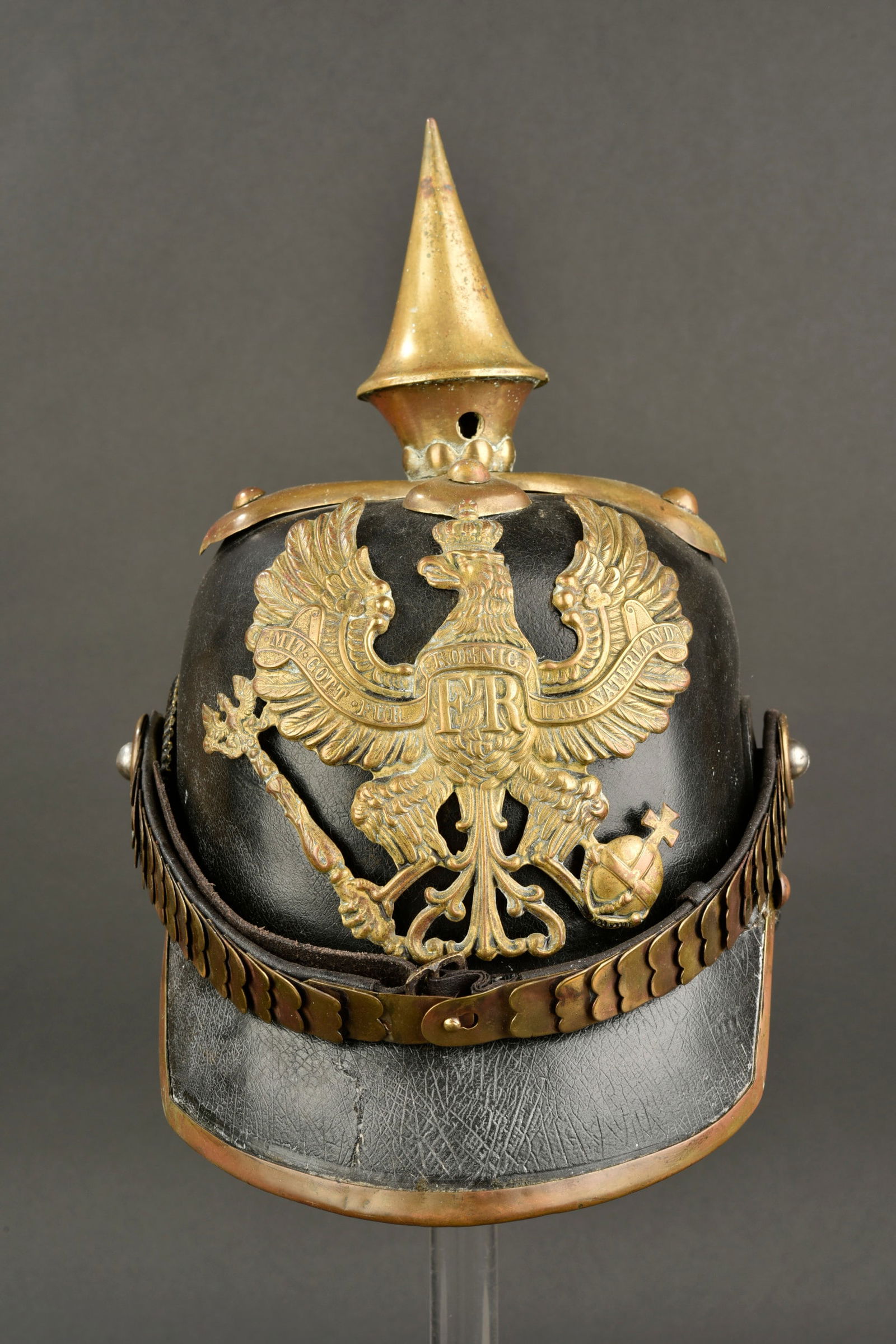 Casque artilleur M1860. M1860 Artillery helmet.: Casque a pointe M 1860. Coque en cuir noir. Plaque prussienne. La pointe n est pas d emontable. Cocarde en m etal noir et blanche. Jugulaire en ecailles dor ees. Coiffe en cuir compl ete. Le cordon de
