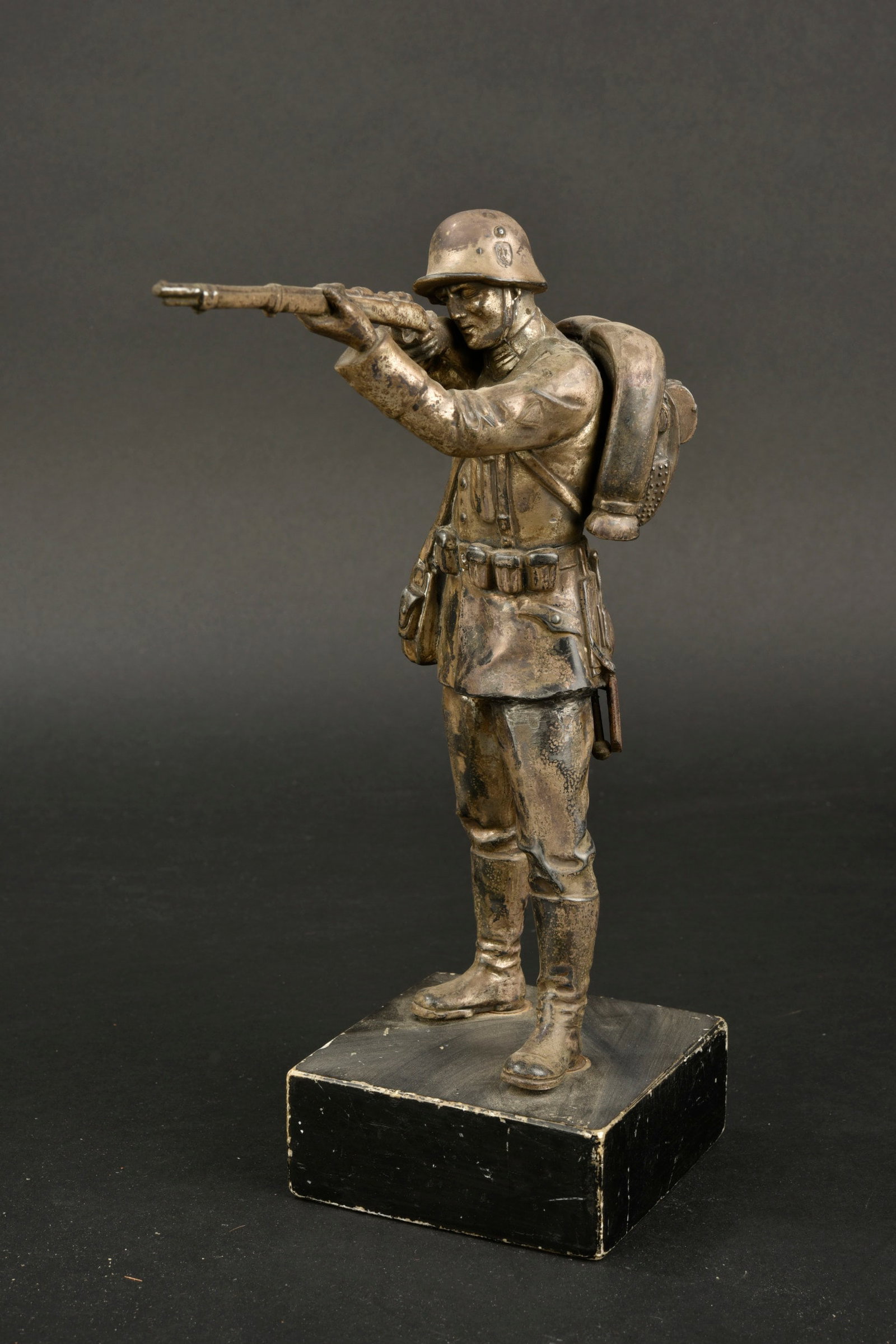Statuette allemande. German figurine.: Statuette allemande. En m etal, couleur argent a 80%. Tr es belle patine. Repr esentant un soldat allemand en position de tir et disposant de tout son mat eriel. Le sac a dos pr esente un certain jeu.