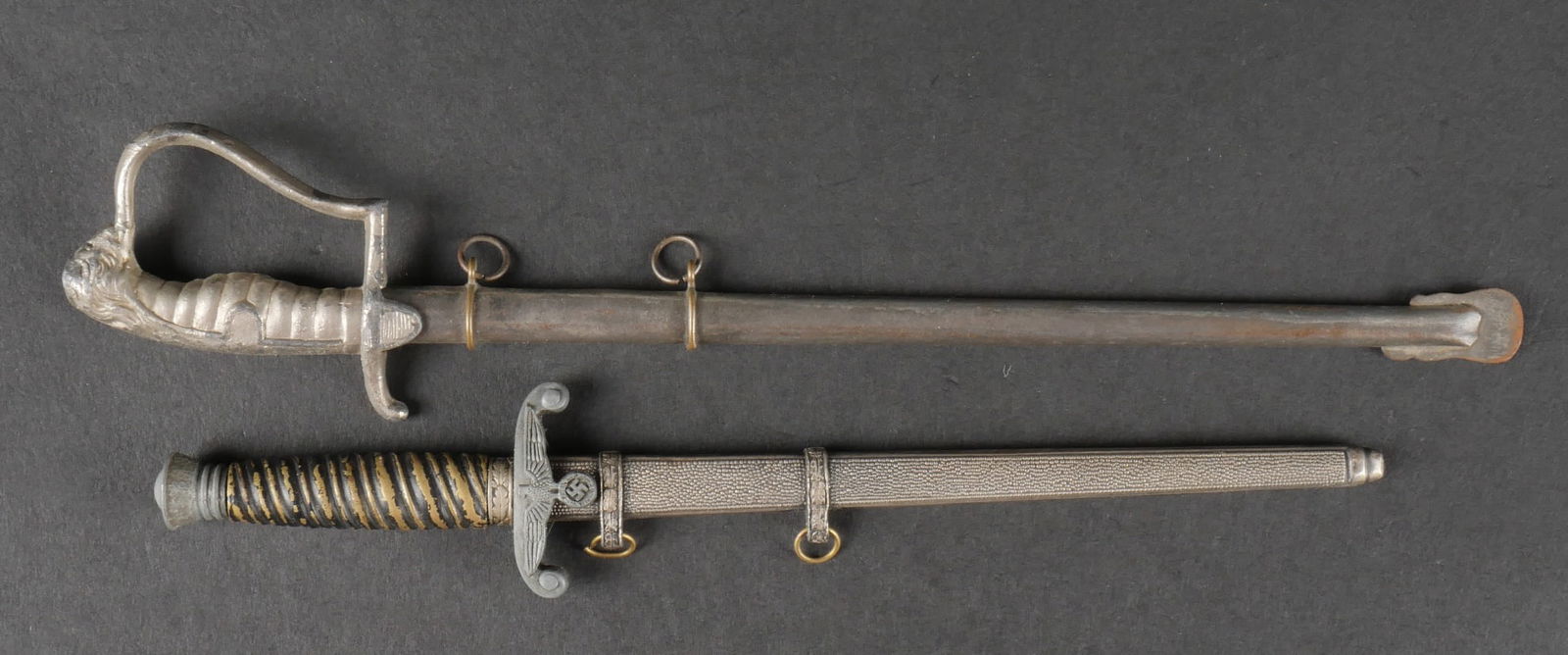 Miniatures de dague. Miniature daggers.: Miniatures de dague. Comprenant une miniature de dague de la Heer, reste de couleur or au niveau de la poign ee. Lame et fourreau en tr es bon etat. Longueur totale 19,5 cm. Une miniature d ep ee de l