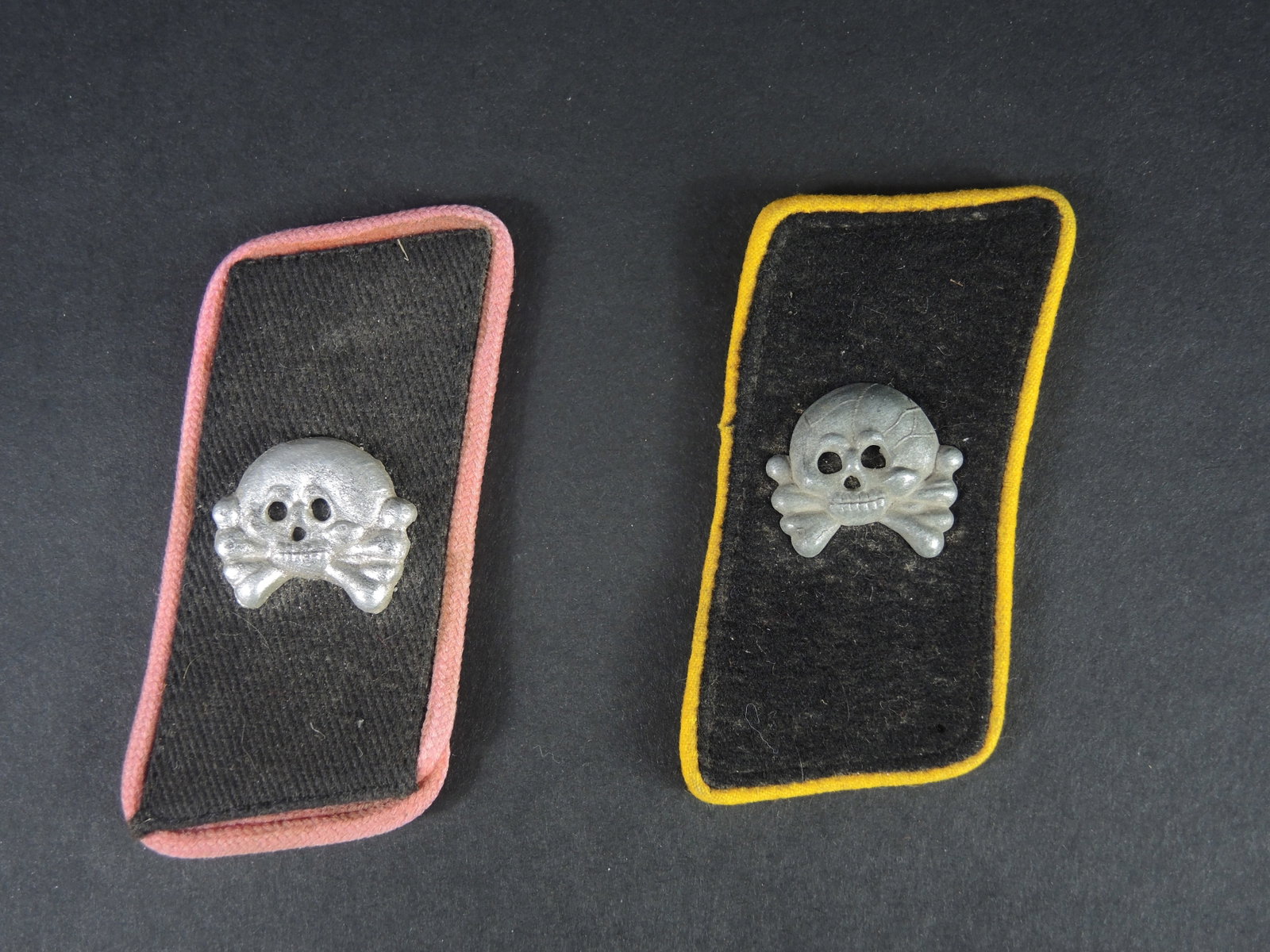 Pattes de col panzer. Panzer collar tabs.: Pattes de col panzer. Comprenant une patte de col en drap noir, liser e jaune, t ete de mort m etallique. Une patte de col en drap noir, liser e rose, t ete de mort m etallique. A noter une certaine u