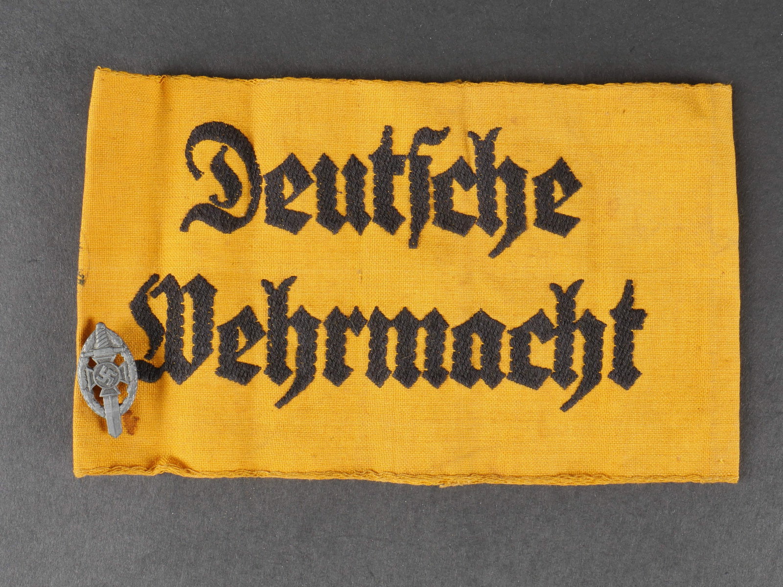 Brassard Deutsche Wehrmacht. German armband.: Brassard Deutsche Wehrmacht. En tissu coton jaune. Marquage brod e Deutsche Wehrmacht. Tampon illisible au dos. Insigne des anciens combattants fix e sur le brassard. A noter une certaine usure et pat