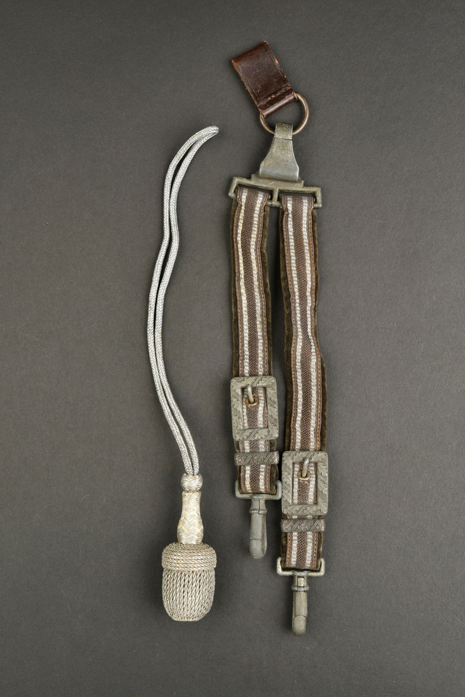 B eli eres LW. Luftwaffe dagger straps.: B eli eres de la Luftwaffe. En tissu gris/bleu et liser e argent. Parties m etalliques a d ecors de feuilles de ch ene. Mousquetons fonctionnels. Marquages DRGM. On y joint une dragonne tress ee de fi