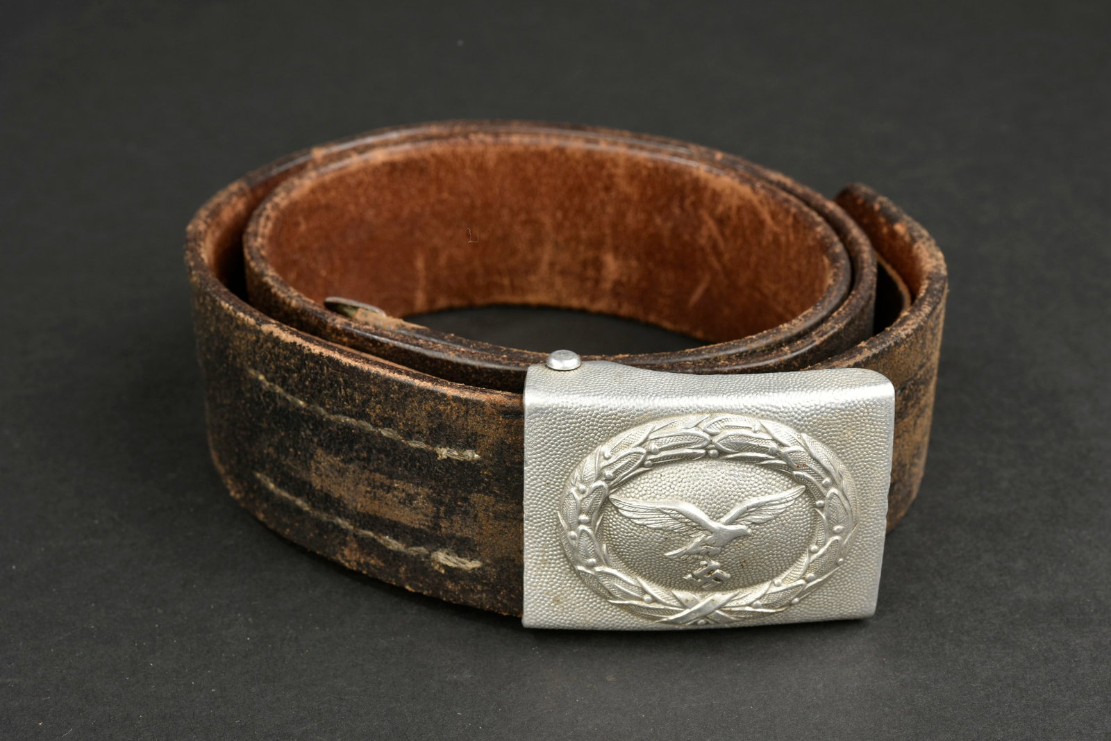 Ceinturon LW. Luftwaffe belt.: Ceinturon de la Luftwaffe. Ceinturon en cuir noir, bouclerie en m etal dans sa couleur d origine a 70%. Patte de r eglage pr esente. Les marquages sont illisibles. Boucle de ceinturon en aluminium gre