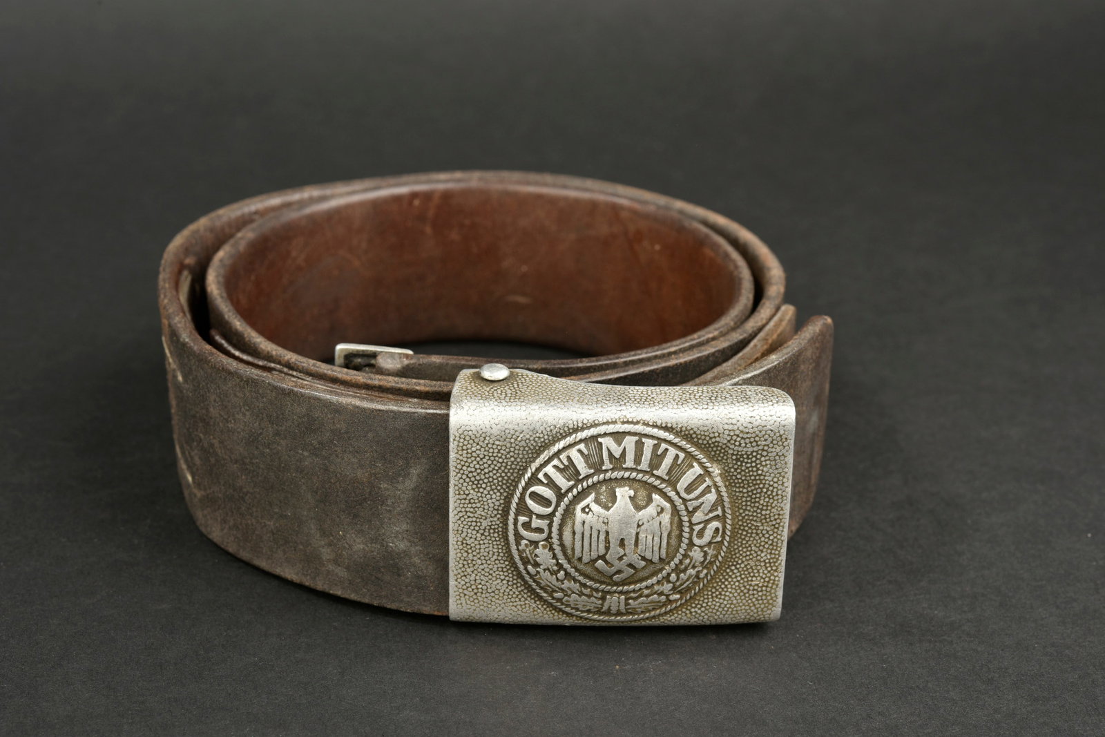 Ceinturon allemand. German belt.: Ceinturon allemand. En cuir noir, patte de reglage presente. Bouclerie en metal. Marquages illisibles, date 1938. Boucle de ceinturon en aluminium grenele, sans marquages visibles. Patte en cuir compl