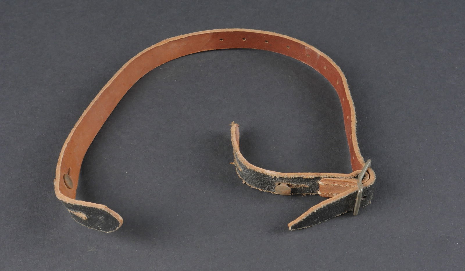 Jugulaire de casque allemand. German helmet chinstrap.: Jugulaire de casque allemand. En cuir noir. Complete. Marquages RFNr 0/0494/0008. A noter une legere usure et patine de la piece. Etat II+. German helmet chinstrap. In black leather. Complete. RFNr ma