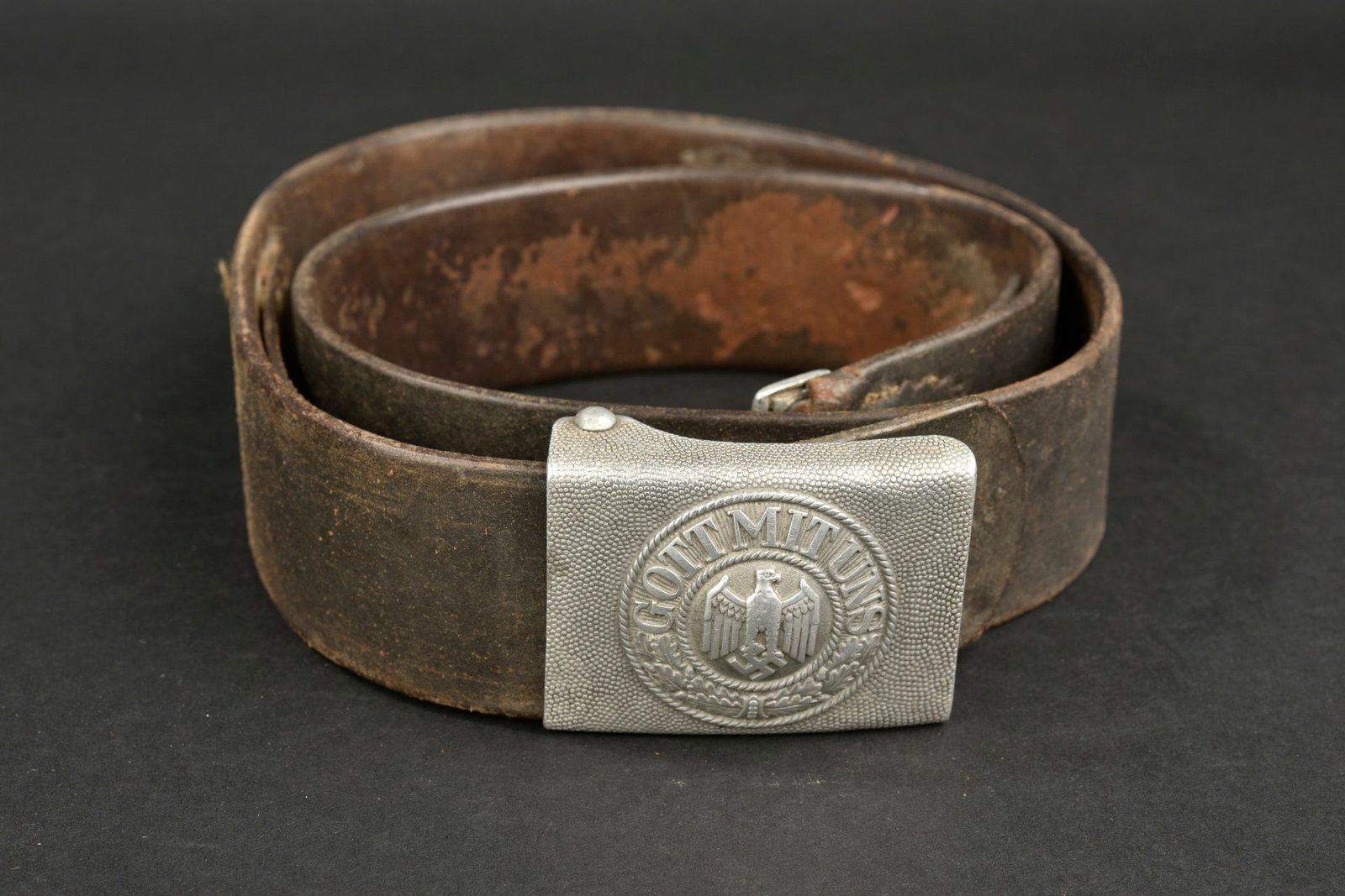 Ceinturon de la Heer. German Heer belt.: Ceinturon de la Heer. Ceinturon en cuir noir. Bouclerie en metal, fabrication OLC. Taille 95. Marquages presents mais illisibles. Patte de reglage complete, coutures defaites. Boucle de ceinturon en a