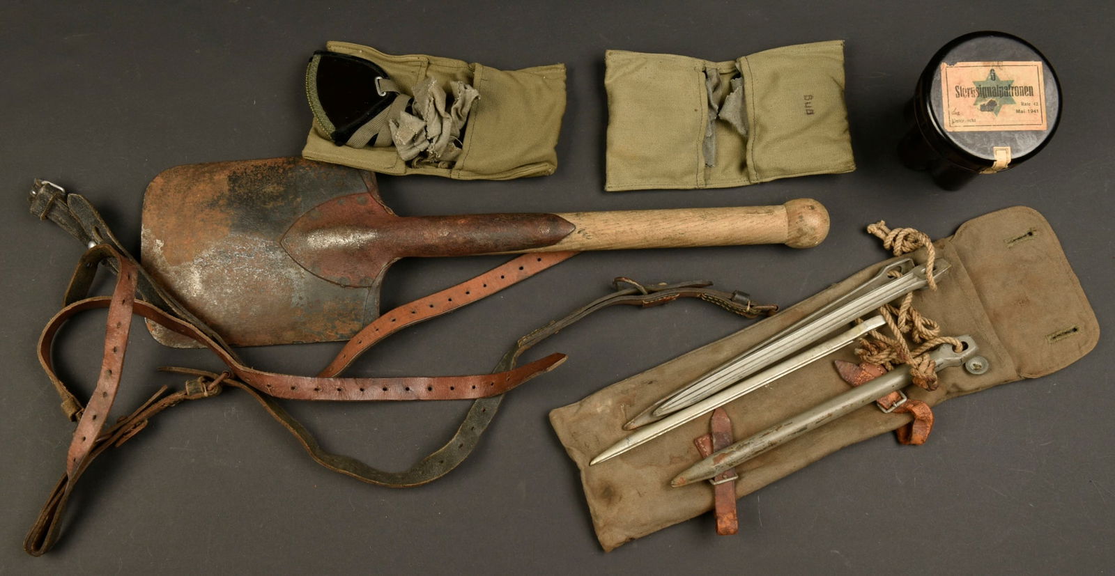 Equipement allemand. German equipment.: Equipement allemand. Comprenant quatre sangles en cuir, les marquages sont illisibles. Un boitier vide en bakelite noir, etiquette marquee 6 Sternsignalpatronen, date mai 1941. Une pelle, manche en bo