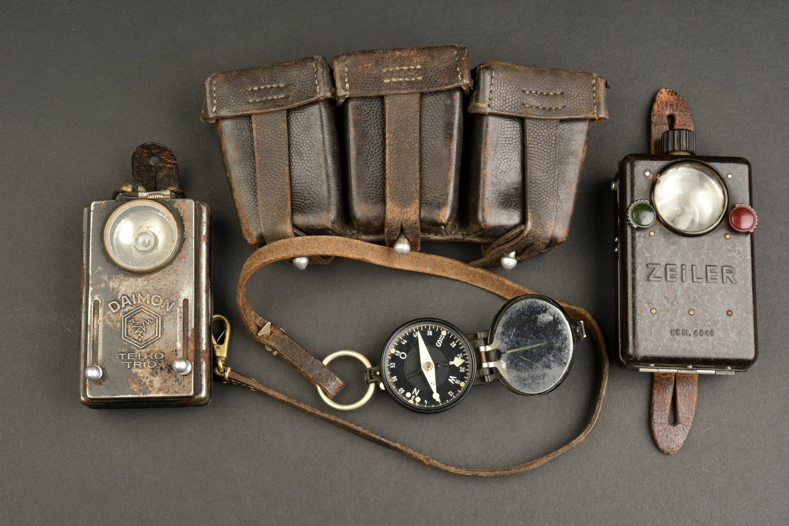 Equipement allemand. German equipment.: Equipement allemand. Comprenant une lampe de poche en metal, marque Daimon Telko Trio, pile moderne presente, ainsi que l ampoule et les passants en cuir. Une boussole fonctionnelle, marquee Busch Rat