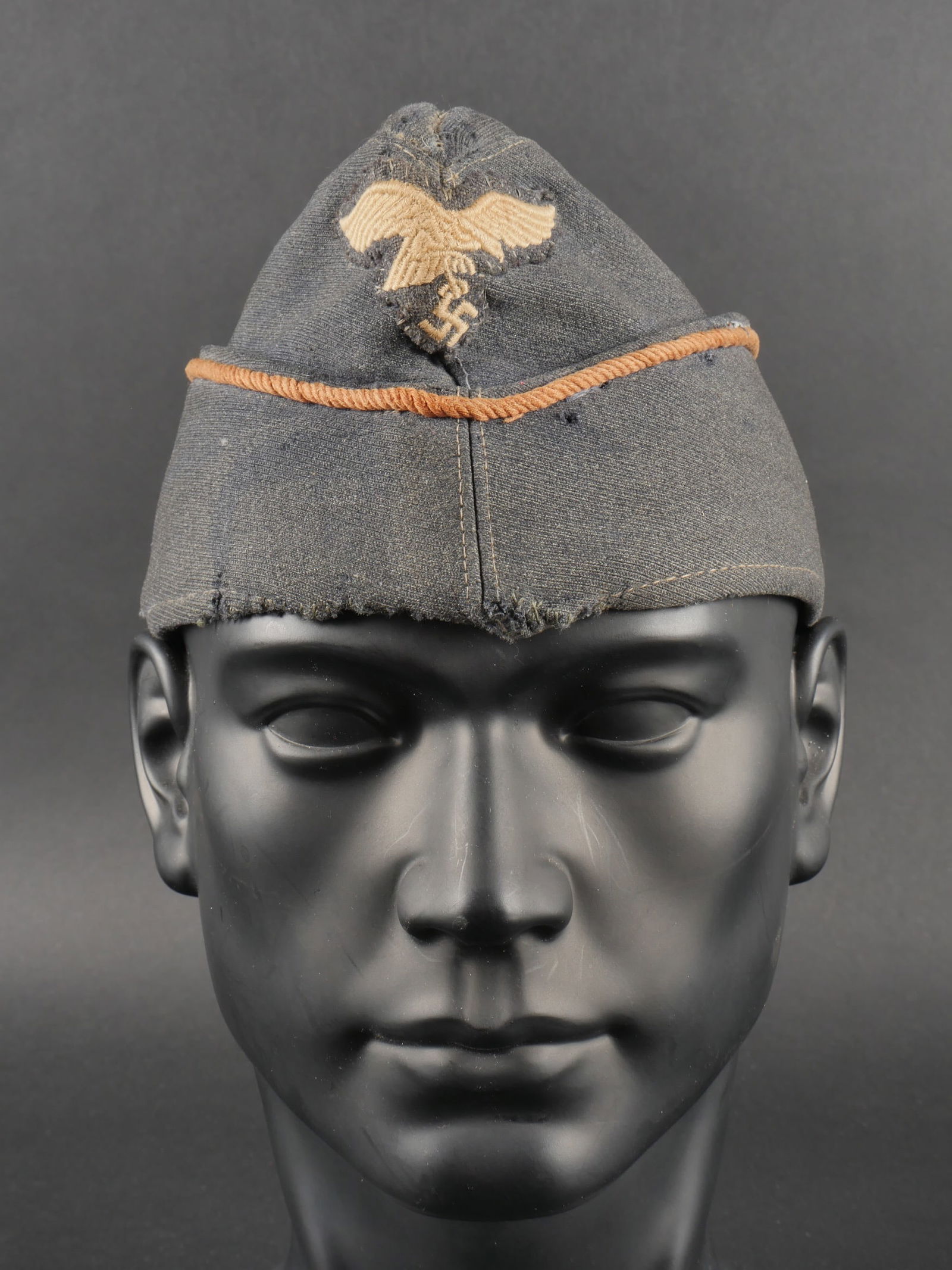 Calot Luftwaffe. Luftwaffe cap.: Calot Luftwaffe. En drap gris bleu. Lisere tresse marron des transmissions. Aigle tisse du second type, remonte. Cocarde manquante. Interieur double en tissu soyeux gris. Etiquette portant les monogra