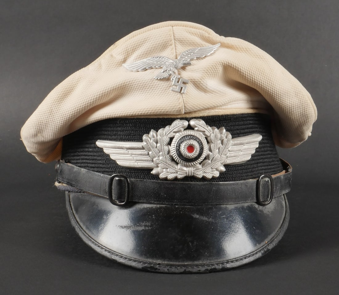 Casquette Luftwaffe. Herman Goring cap.: Casquette de sous-officier de la Luftwaffe. Coiffe en tissu coton blanc, probablement posterieure. Bandeau en mohair noir. Double lisere blanc des division Hermann Goring. Insignes metalliques. Les in