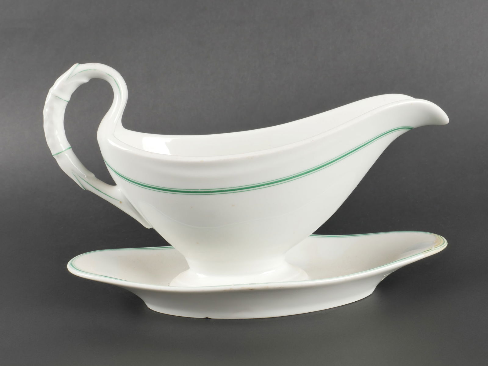 Sauciere de la Kriegsmarine. Kriegsmarine sauceboat.: Sauciere de la Kriegsmarine. En porcelaine blanche. Lisere vert. Quelques eclats visibles sur les bordures. Bel insigne Kriegsmarine. Fabrication KPM 1941. Une reparation visible sous la sauciere. A n