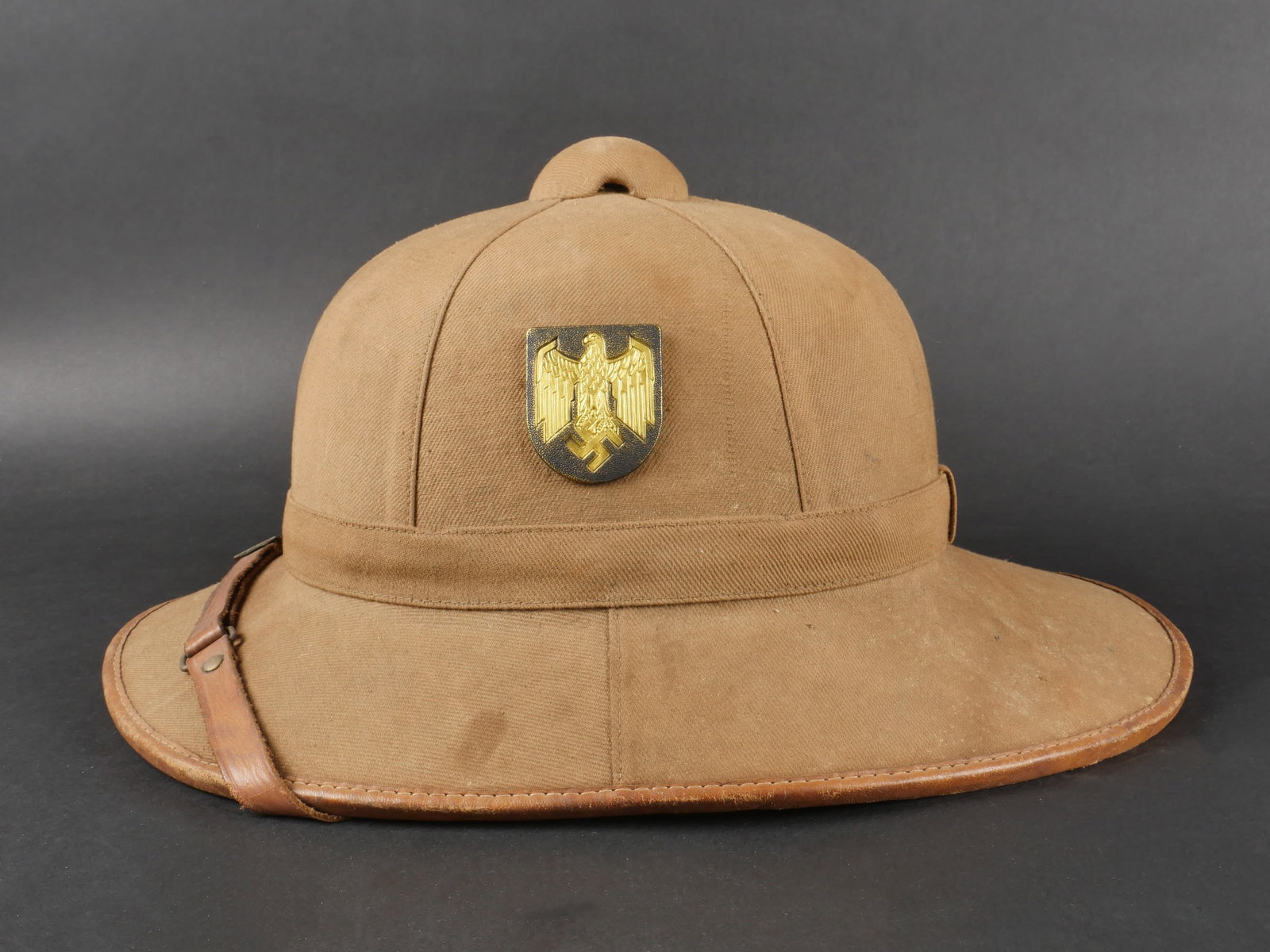 Casque tropical Kriegsmarine. German Kriegsmarine tropical helmet.: Casque tropical de la Kriegsmarine. En liege recouvert d un tissu beige. Pourtour en cuir fauve. Les insignes metalliques sont present, mais dont l authenticite n est pas garantie. Fausse jugulaire en