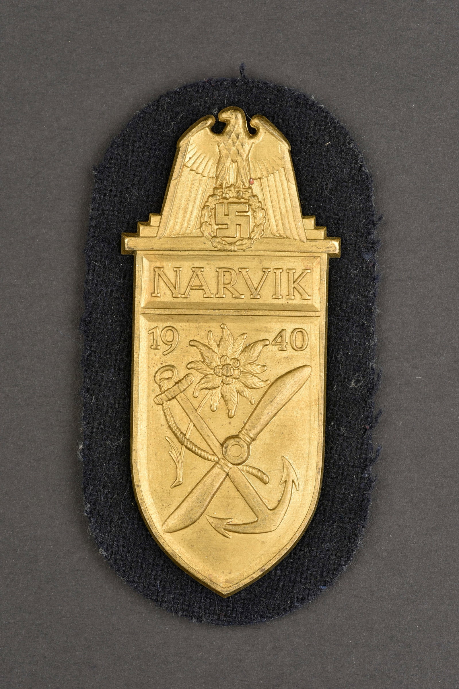Plaque Narvik. German Narvik insignia.: Plaque Narvik. En metal embouti couleur or. Monte sur un drap de couleur noir, typiquement de la Kriegsmarine. Dos de la piece double d un fin papier gris vert.a noter une certaine usure et patine de 