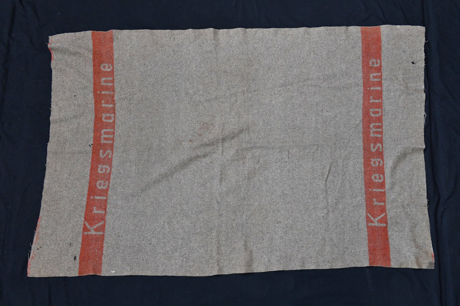 Couverture Kriegsmarine. Kriegsmarine coverage.: Couverture Kriegsmarine. En tissu laineux marron. Bande rouge marquee Kriegsmarine.a noter une certaine usure et patine de la piece,ainsi que quelques trous de mite. Etat II+. Kriegsmarine blanket. Br