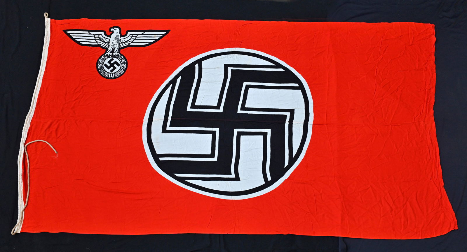 Drapeau Kriegsmarine. Kriegsmarine flag.: Reichskriegsflagge. En tissu coton rouge. Insigneallemand imprime. Biface. Les cordons de fixationau mat sont presents. Marquages Reichsdienst Gr 8, logo du fabricant present, beau tampon de la Kriegs