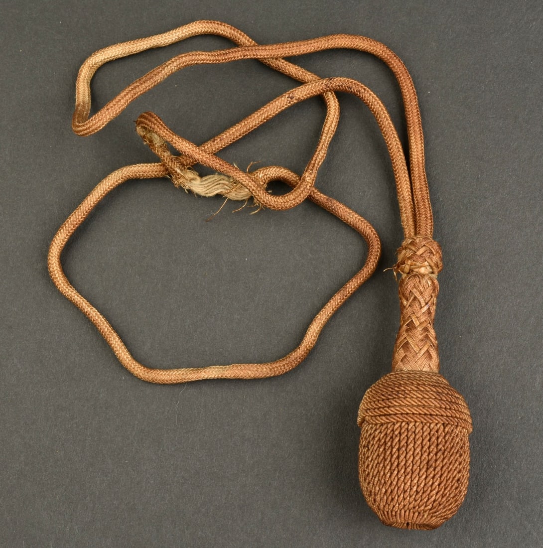 Dragonne Kriegsmarine. Kriegsmarine straps.: Dragonne Kriegsmarine. En fil tresse or. Couleur foncee. Une partie de la dragonne est fortement effilochee.a noter une certaine usure et patine de la piece. Etat II+. Kriegsmarine lanyard. In gold br