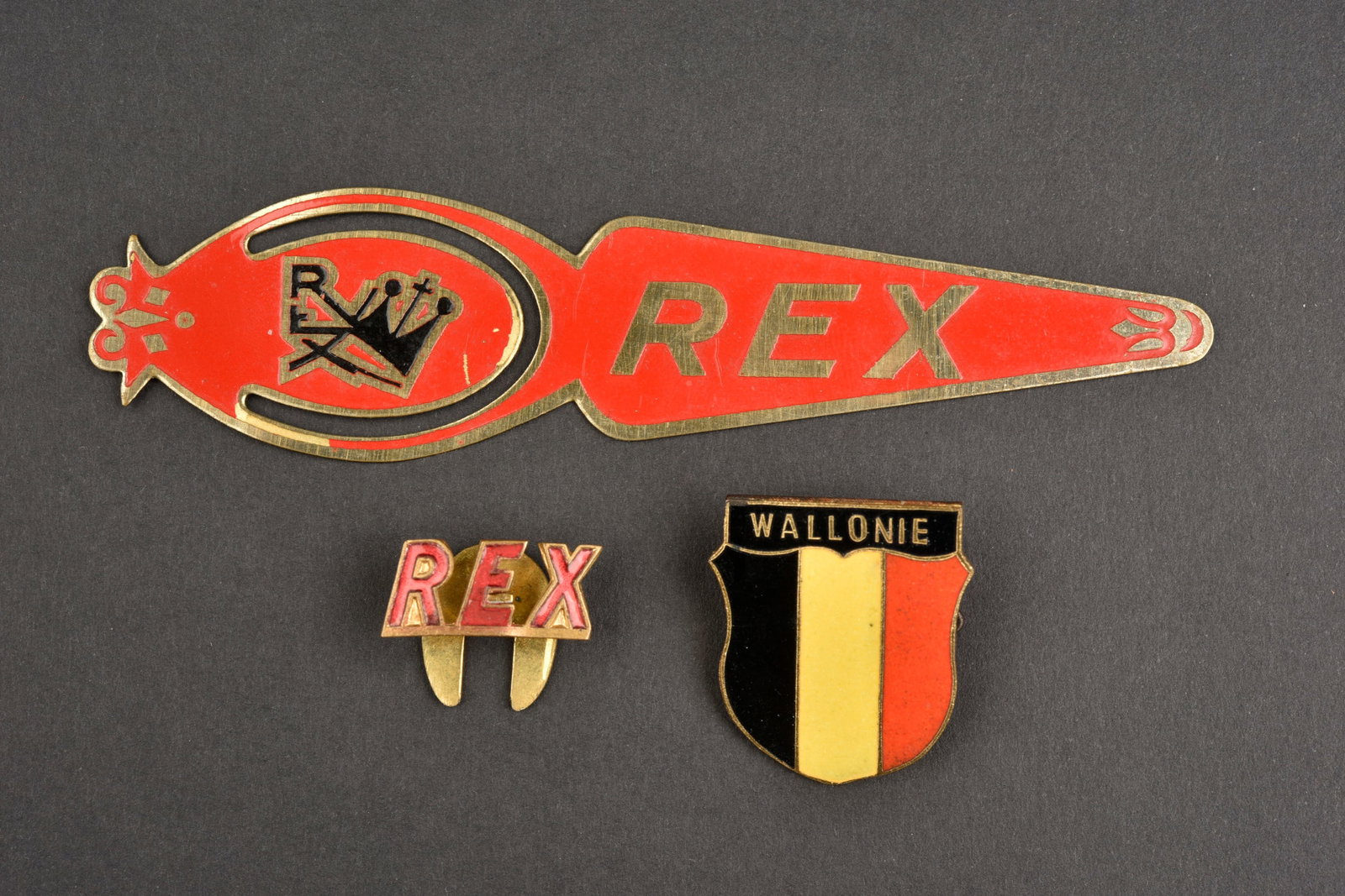 Lot Rex. Rex lots.: Lot REX. Comprenant un petit coupe papier en metal et en couleur de REX. Un insigne en metal emaille marque Wallonie,attache complete. Un insigne boutonniere marque REX, sans marquages visibles.a note