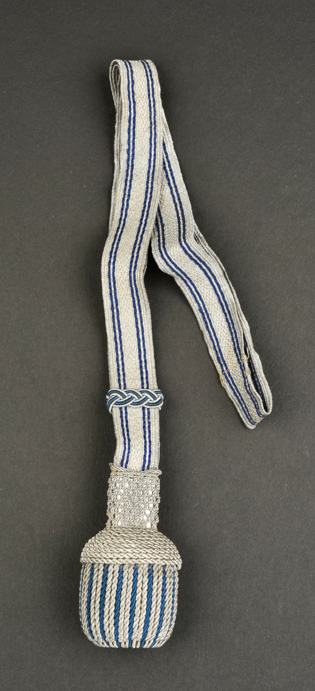Dragonne DRK. German DRK straps.: Dragonne DRK. Laniere en tissuargent et liseres bleu. Gland tresseargent et bleu. Fond du gland de couleur bleu, presentant des traces de mite.a noter une certaine usure et patine de la piece. Etat II