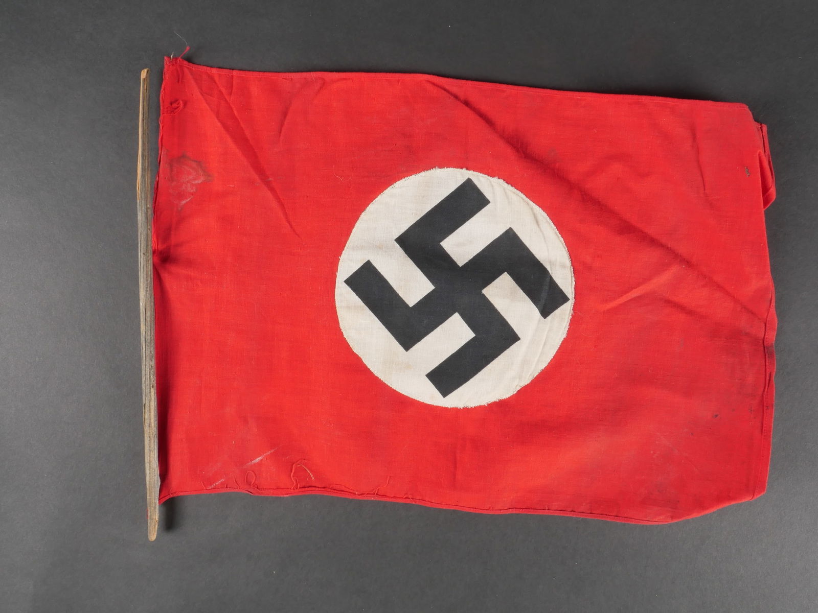 Fanionallemand. German flag.: Fanionallemand. En tissu coton rouge biface. Insigne national imprime et rapporte. Fixation sur un mat en bois, fortementabime. Dimensions 26 x 39 cm.a noter une certaine usure et patine de la piece,a
