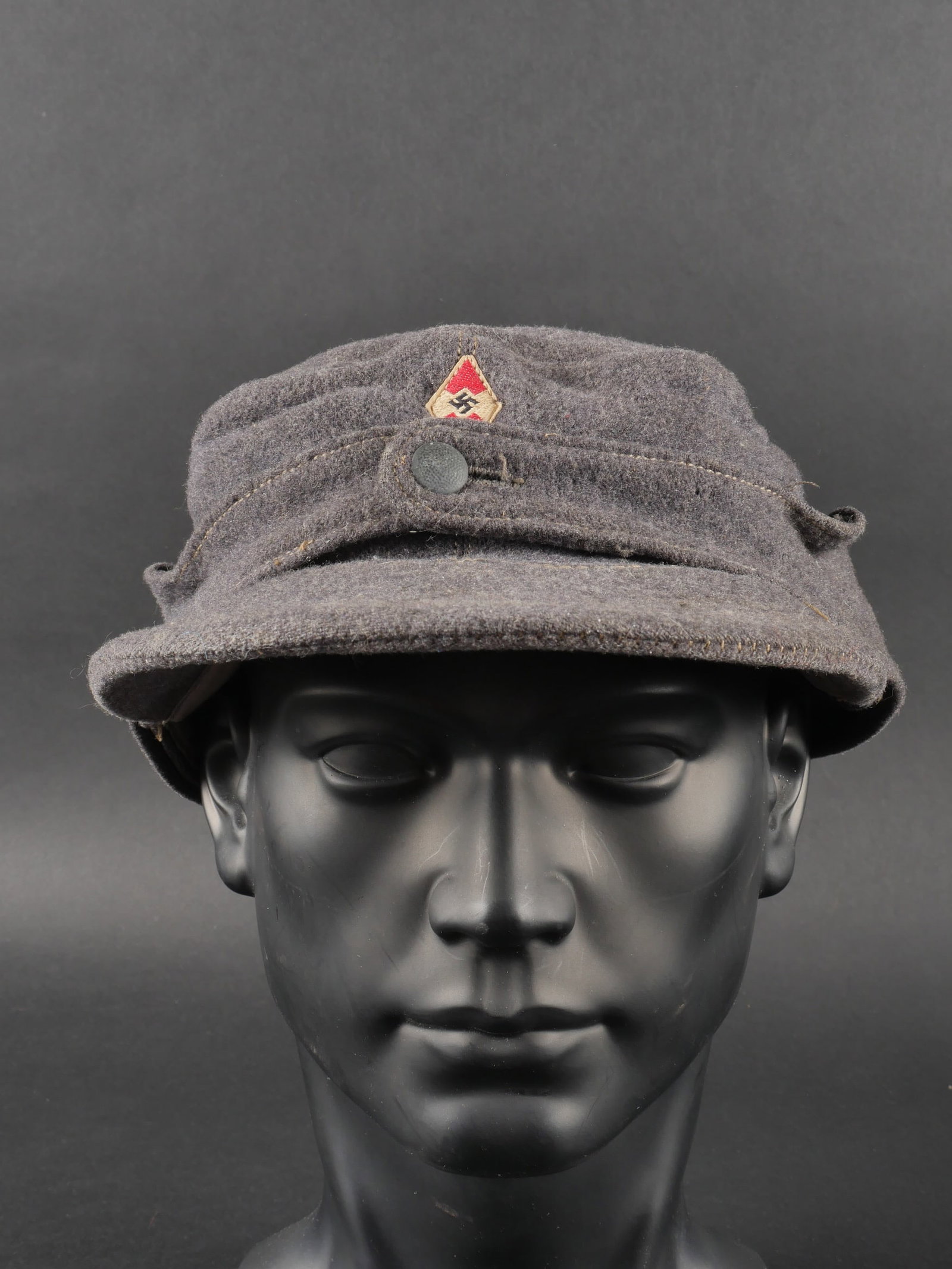 Casquette Hitlerjugend. Hitlerjugend cap.: Casquette Hitlerjugend. En drap gris bleu. Un bouton grenele bleu fermant le rabat. Deux œillets d aeration. Insigne Hitlerjugend tisse monte machine. Interieur double en satinette grise. Marquages 6