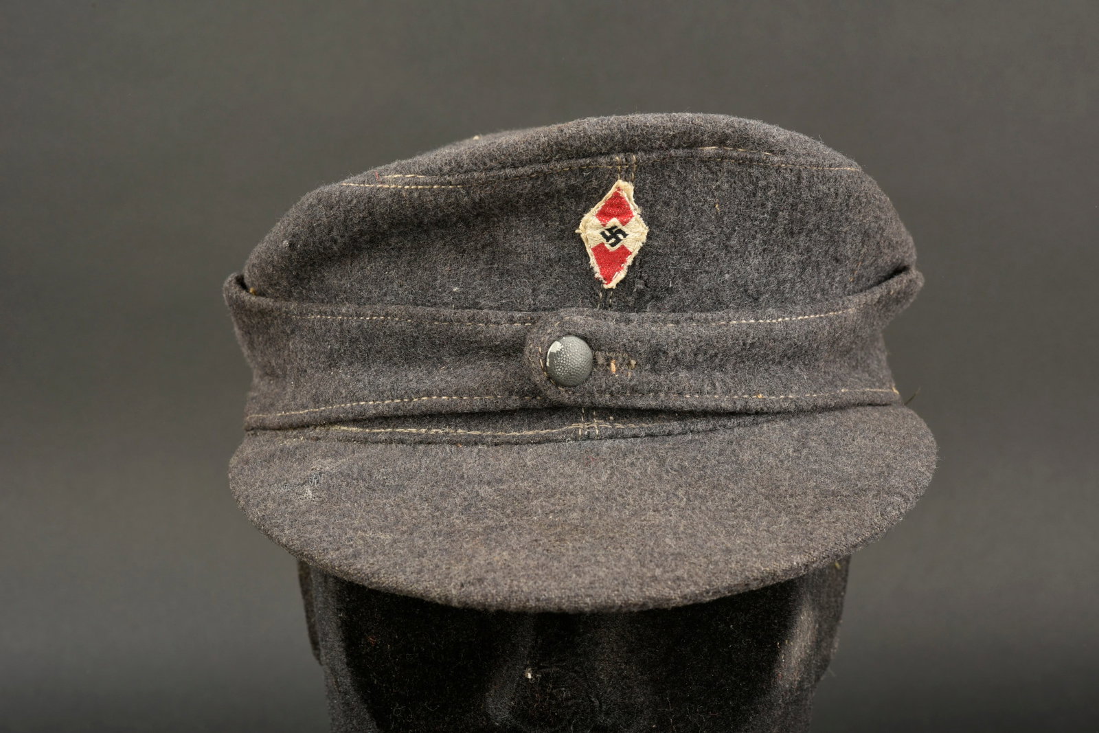 Casquette HJ. Hitlerjugend cap.: Casquette Hitlerjugend. En drap gris bleu. Rabat fermant Un bouton grenele. Insigne en metal emaille. Insigne tissu visiblement cousu machine. Interieur double en tissu molletonne gris. Marquages 016 