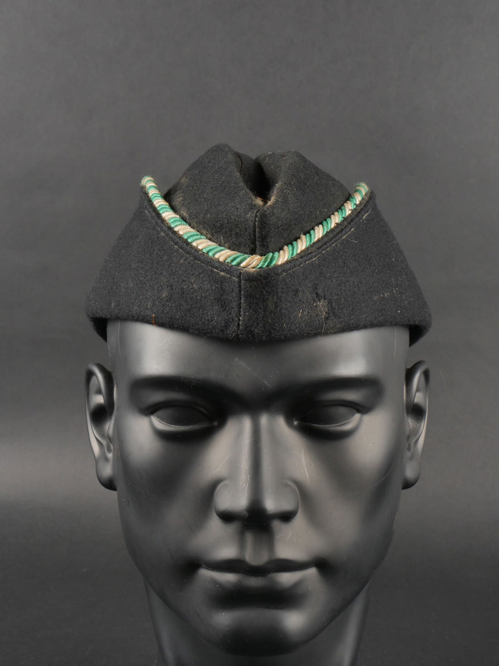 Calotallemand. German cap.: Calotallemand. En drap noir. Lisere tresse vert et blanc faisant le tour de la coiffure. Pompon de la meme couleur presentau dos de la piece. Sans insignes. Interieur double en tissu noir. Etiquette R