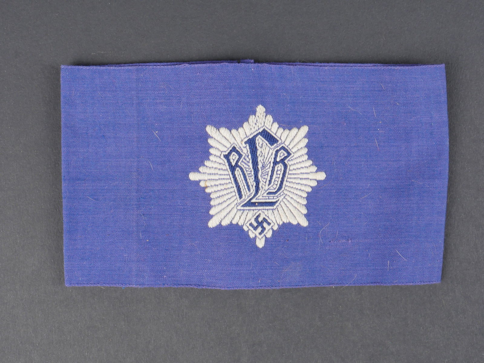 Brassard RLB. German RLBarmband.: Brassard RLB. En tissu bleu. Insigne du RLB brode. Marquages Ges Geschau dos.a noter une certaine usure et patine de la piece,ainsi que quelques taches. Etat II+. RLBarmband. In blue fabric. Embroider