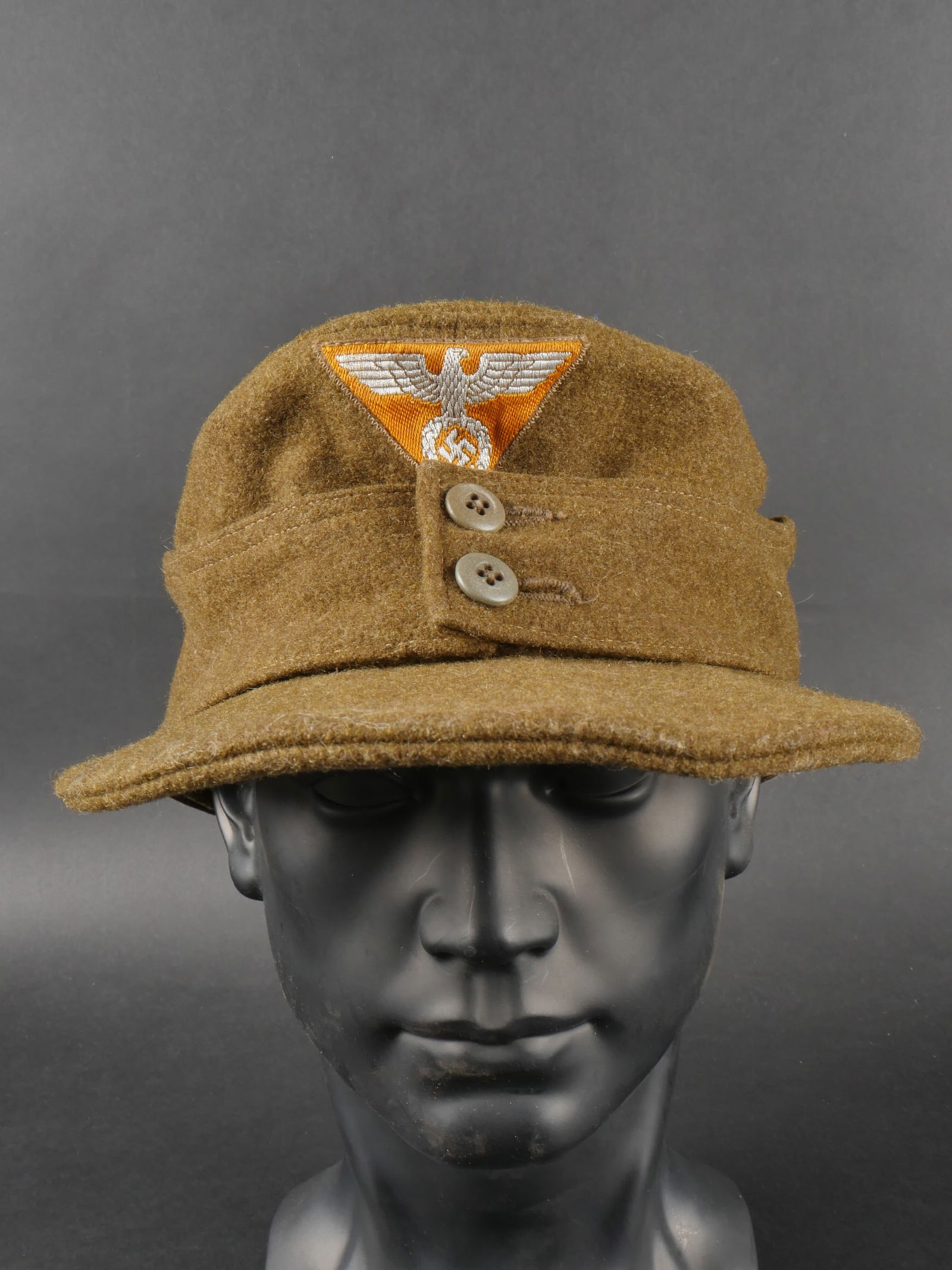 Casquette SA Wehrmanschaft. SA cap.: Casquette SA Wehrmannschaft. En drap kaki. Deux boutons maintenant les rabats. Insignes SA tisse sur fond orange visiblement cousu d origine. Doublure en carton de la visiere dechiree et cassee. Inter