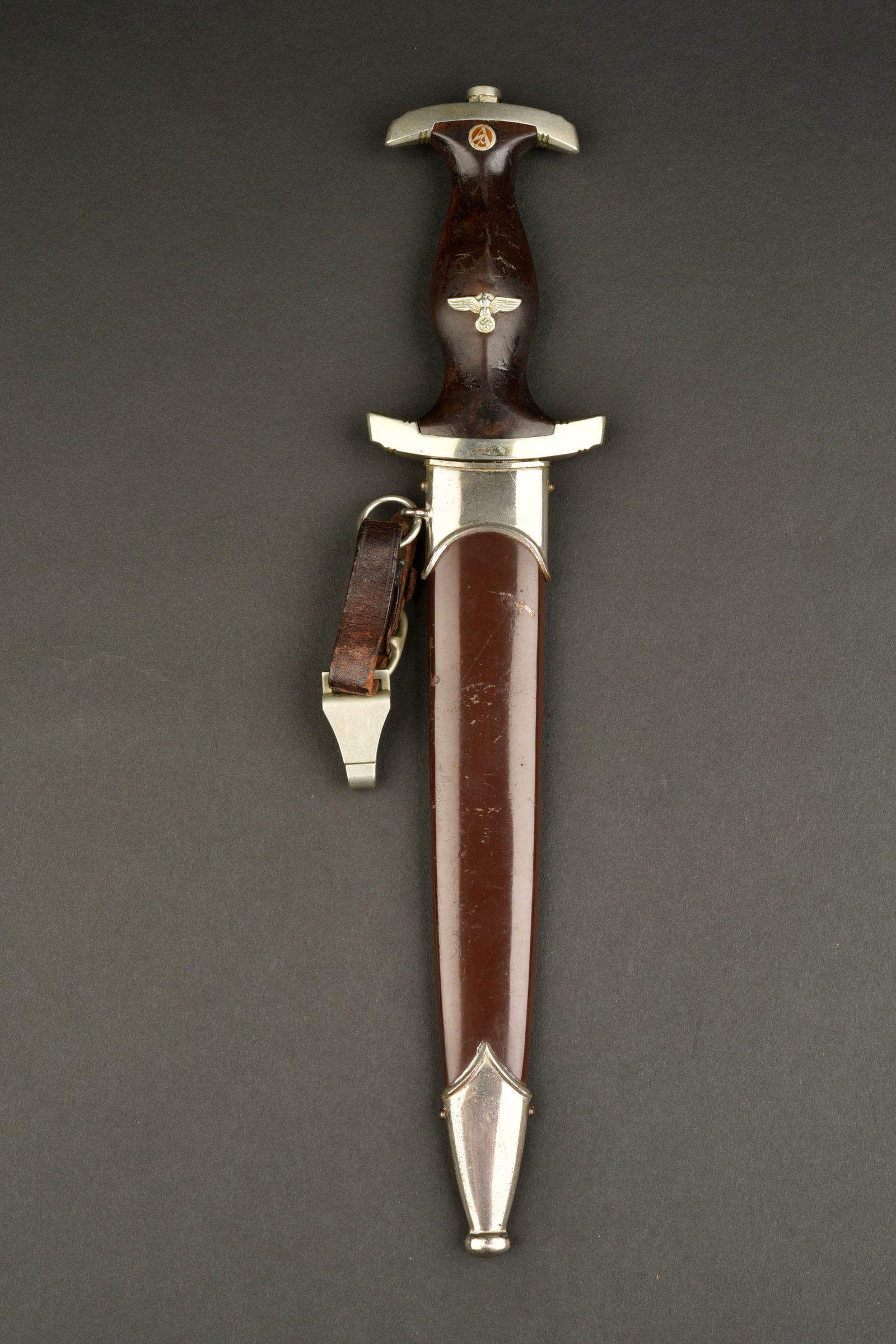 Dague SA. SA Dagger: Dague SA. Poignee en bois tirant sur le brun fonce, traces de verni present. Toutes les garnitures sont en metal. Insigne SA etaigleallemand montes d origine. Garde marquee Nrh. Belle lame presentant