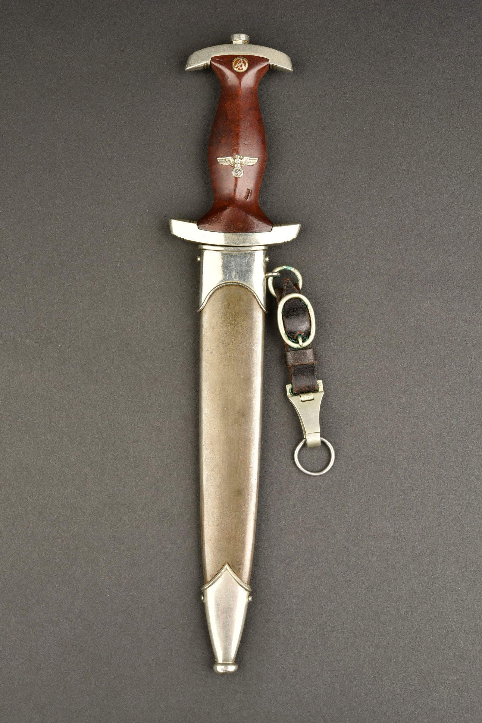 Dague SA. SA Dagger: Dague SA. Garnitures metalliques nickelees. Poignee en bois marron.aigle et insigne SA montes d origine. Un eclat visible sur la poignee. Garde portant le marquage NM et BR 15/40721. Belle lame usee,