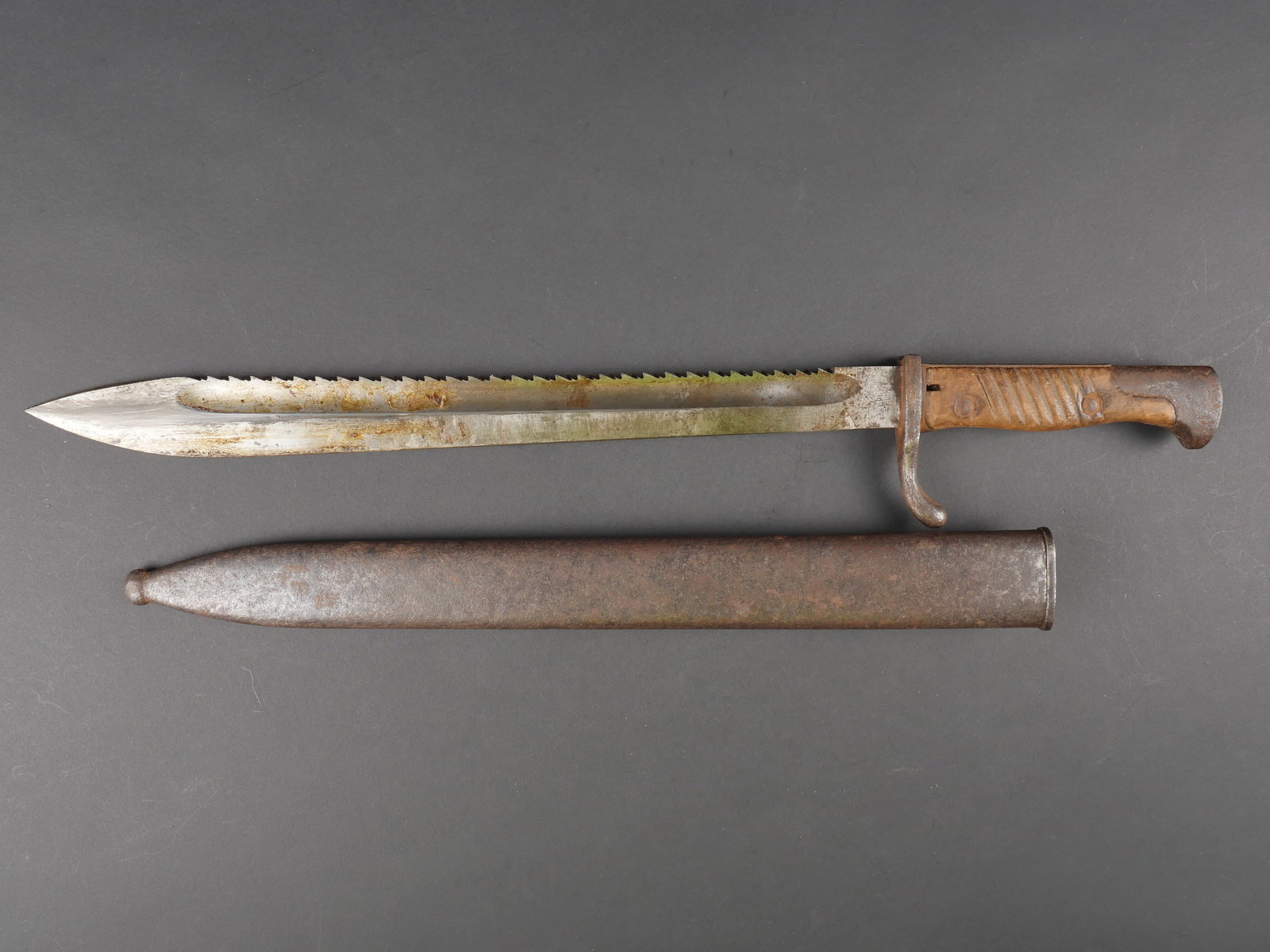 Baionnette 98/05 dents de scie. Bayonet 98/05 with saw teeth.: Baionnette 98/05 dents de scie. Garnitures en metal oxydees. Plaquettes en bois striees. Belle lame partiellement oxydee, a dents de scie. Fabrication C G Haenel Suhl. Datee 1916. Fourreau en metal co
