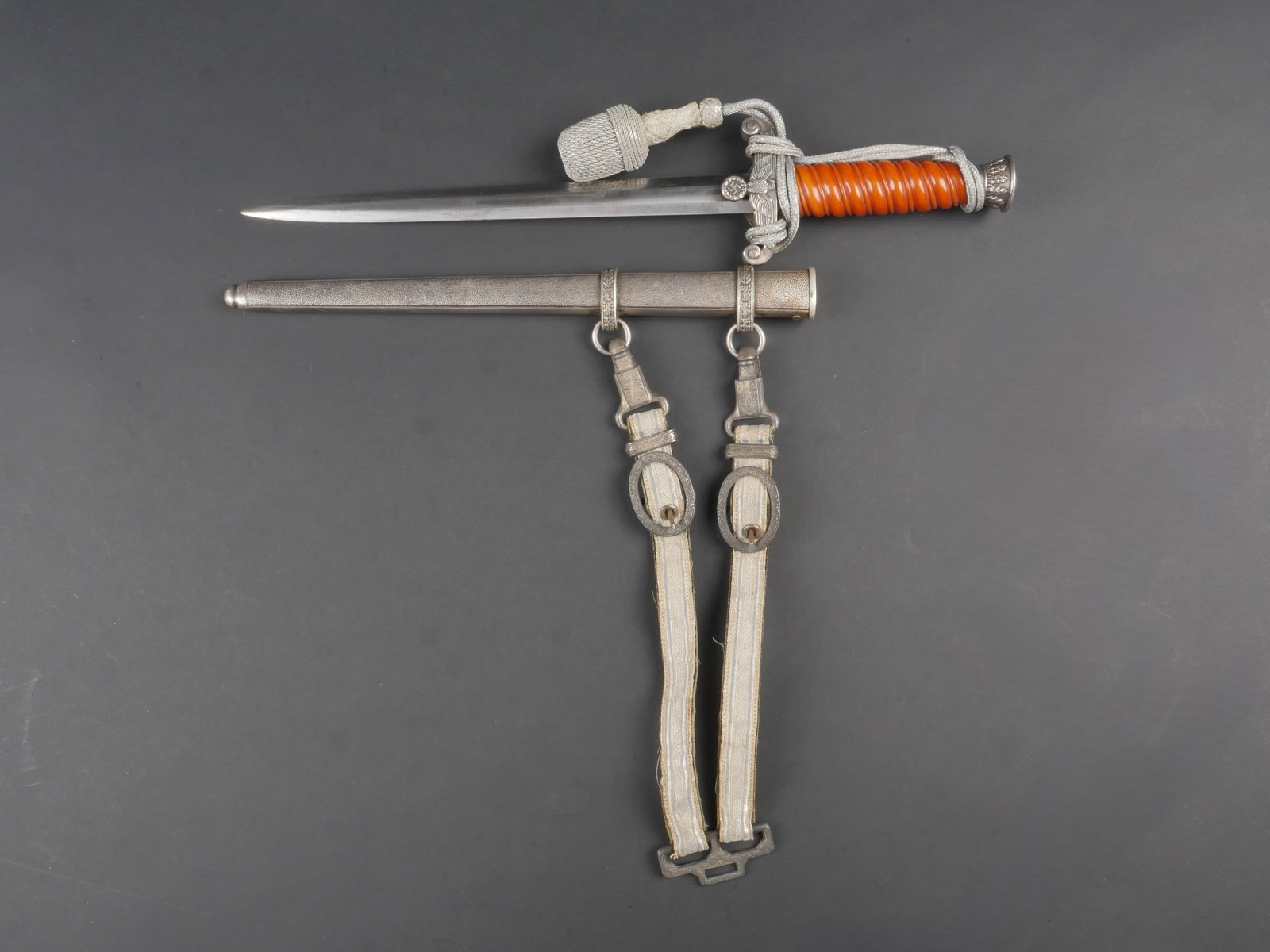 Dague officier Heer. Heer officer dagger.: Dague d officier de la Heer. Garnitures en metal. Poignee en celluloid orange. Bel aigle allemand au niveau de la garde. Lame presentant des marques d usure et d oxydation. Fabrication WKC Solingen. F