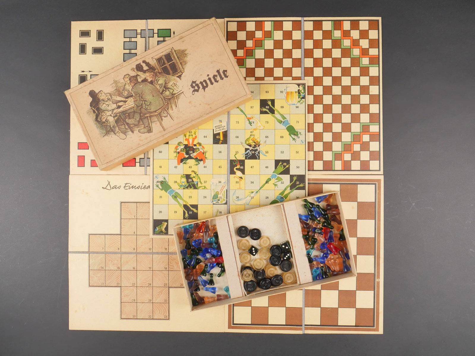 Jeux allemand. German board games.: Jeux allemand. Boite en carton contenant plusieurs jeux. Couvercle joliment decore de soldat allemand jouant. Marquages Spiele. Contenant 5 plateaux de jeux, trois des, 24 jetons, 110 pions colores. A