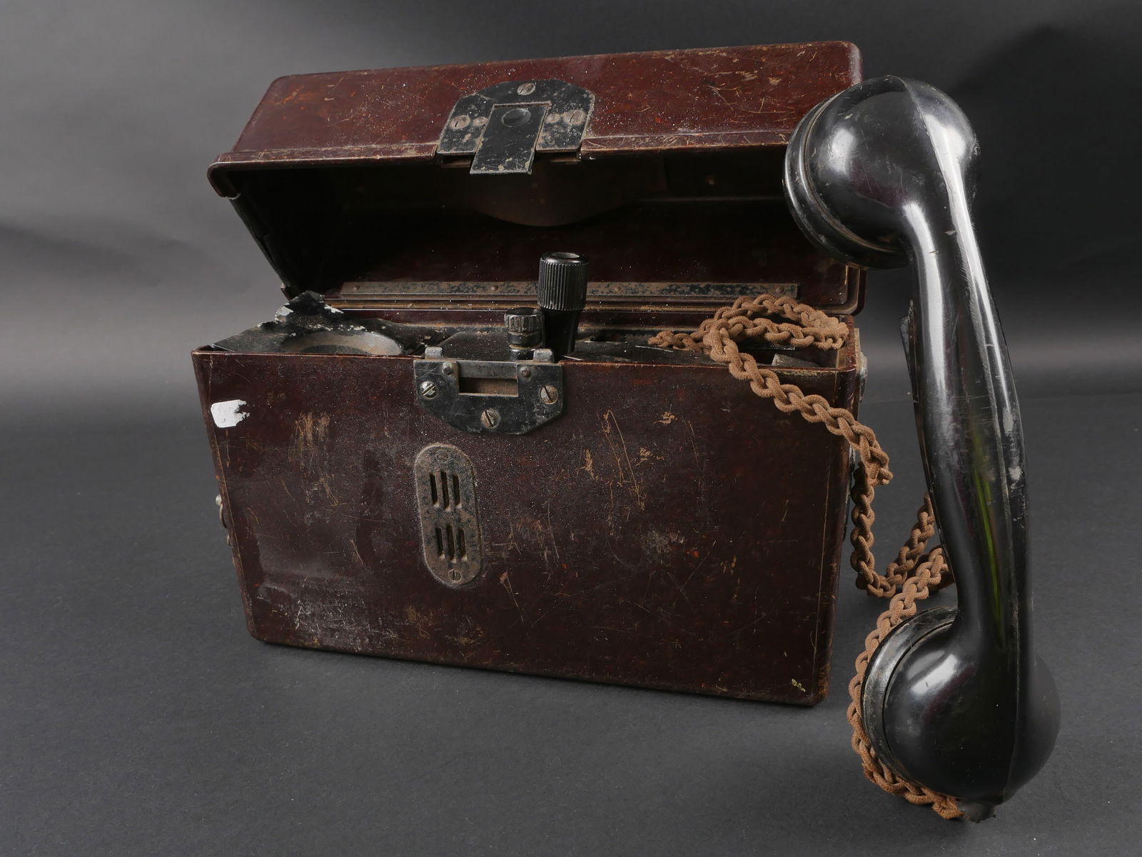 Telephone de campagne.: Telephone de campagne allemand. En bakelite. Prise laterale presente. Le systeme de fermeture est complet. Les plaquettes sur le couvercles sont presentes. Manivelle presente, ainsi que le combine. Fa