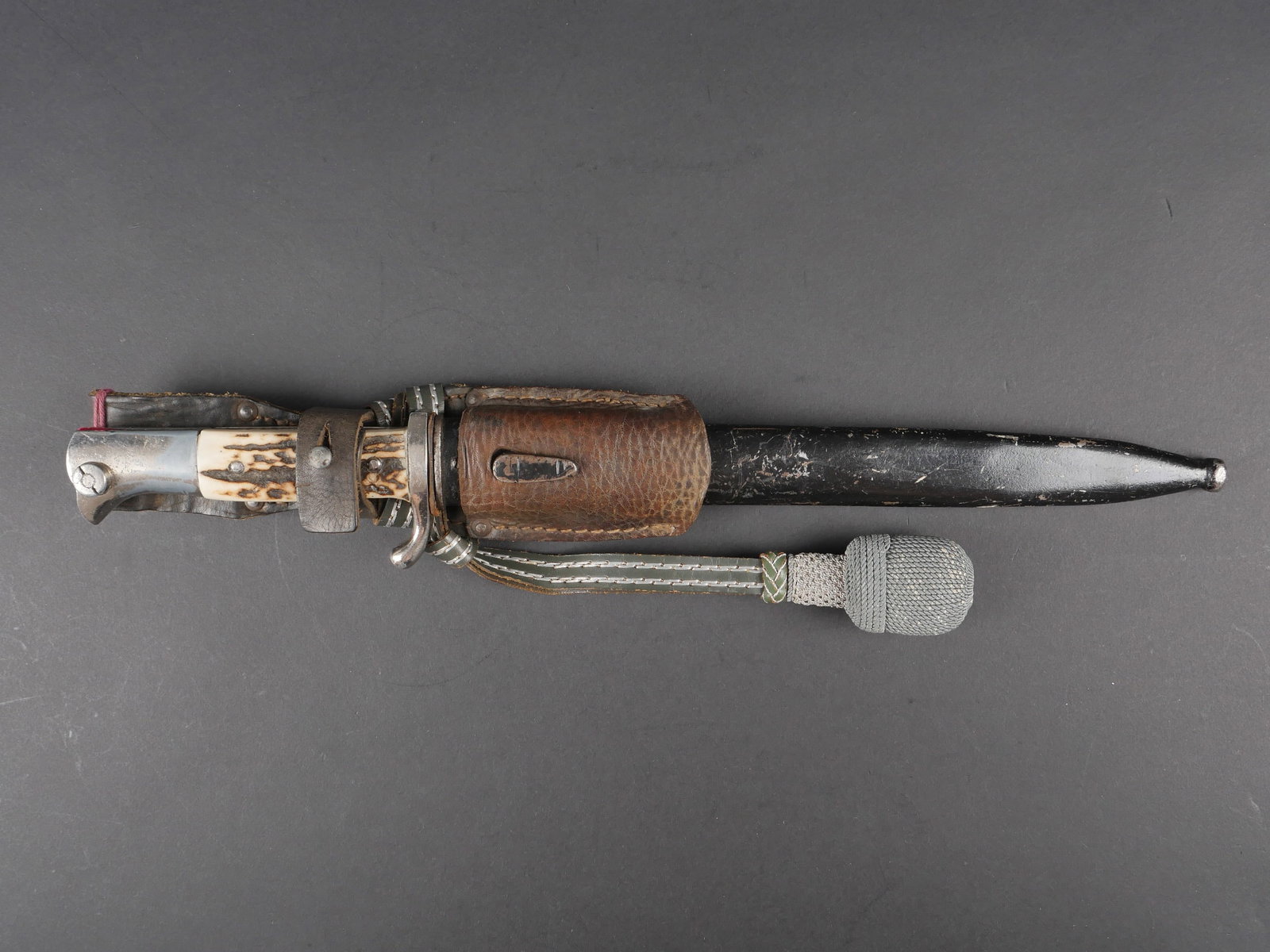 Baionnette de parade. German dress bayonet.: Baionnette de parade. Garniture en metal nickele. Pommeau a tete d aigle. Bouton poussoir fonctionnel. Plaquettes en imitation bois de cerf. Lame dans sa couleur d origine presentant quelques marques 