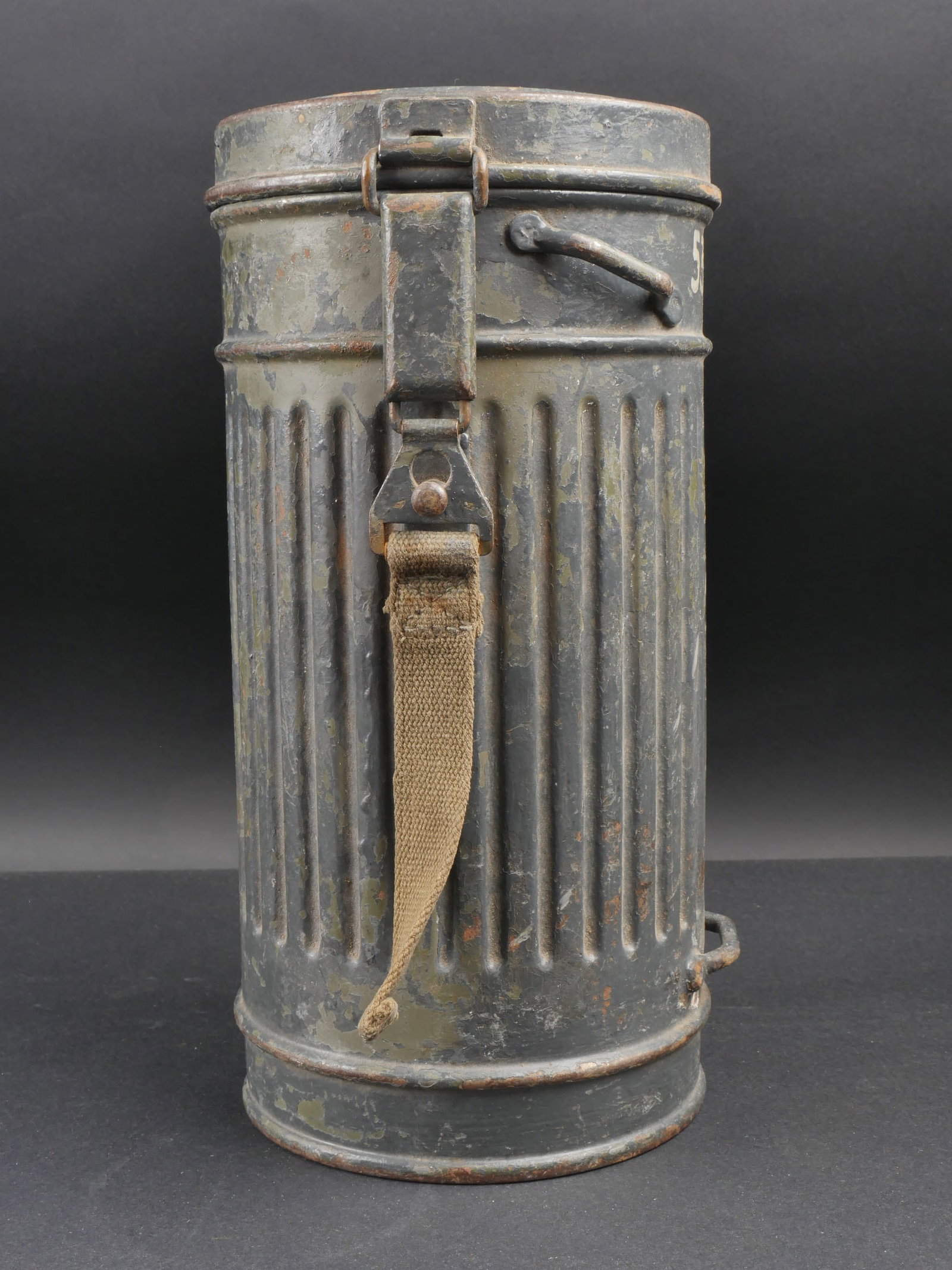 Boitier de masque anti-gaz. German gas mask case.: Boitier de masque anti-gaz. Modele court en metal, marquages 530 sur le cote. Tirette presente. Les deux autres sangles sont manquantes. Peinture a 60%. Quelques bosses visibles. Couvercle date 1937 a