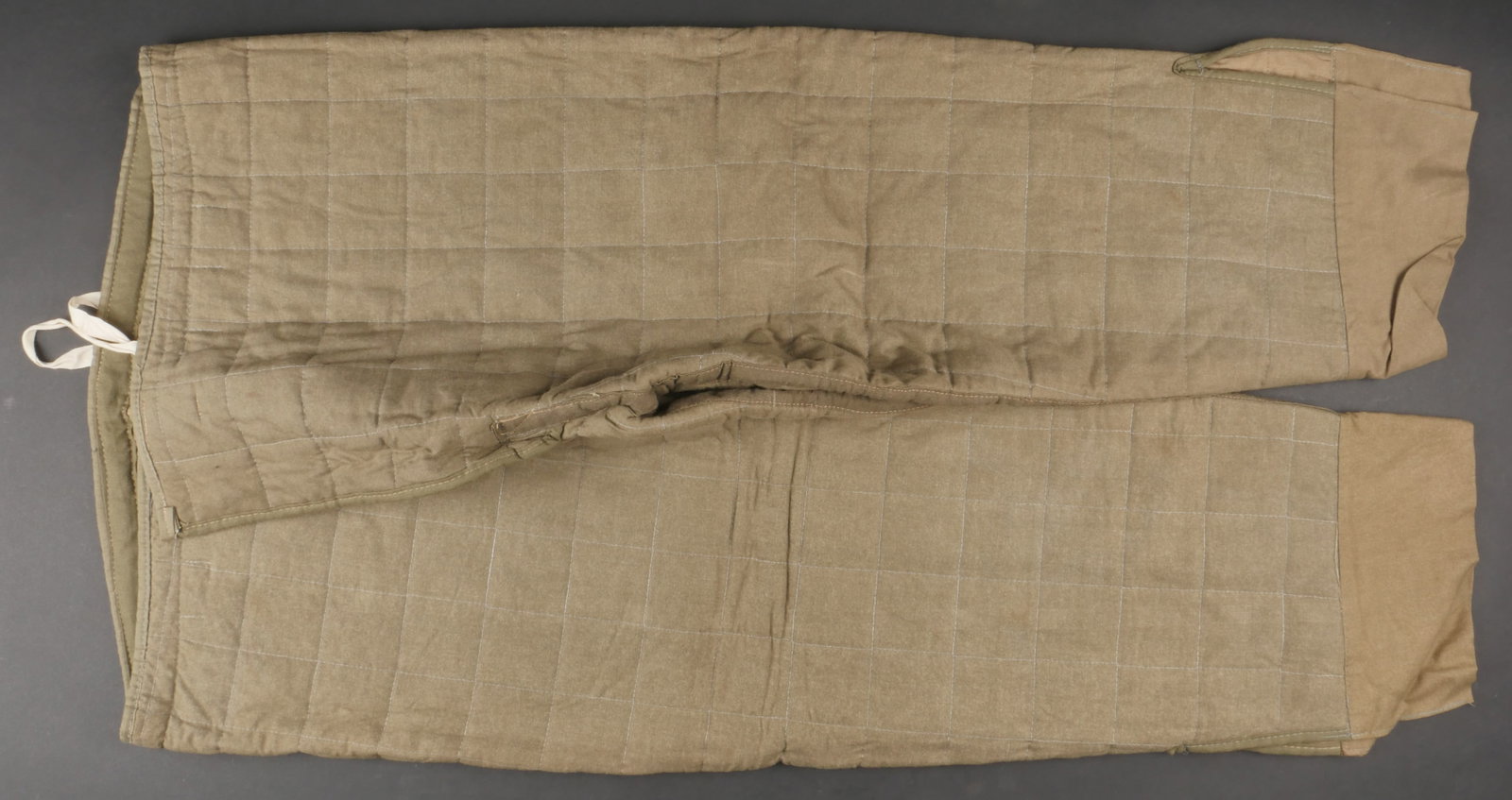 Sur pantalon hivernal. On winter pants.: Sur pantalon hivernal. En epais tissu molletonne. Les cordons de serrage sont presents. Marquages presents mais illisibles. A noter une legere usure et patine de la piece, ainsi que quelques discretes