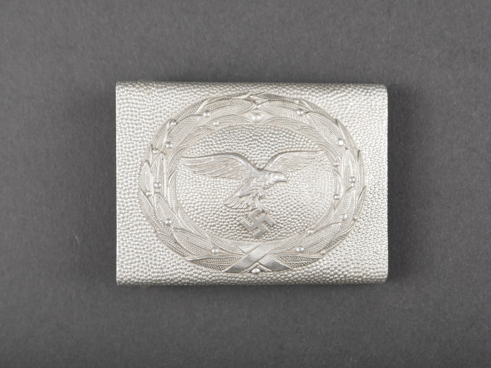 Boucle de ceinturon LW. Luftwaffe belt buckle.: Boucle de ceinturon de la Luftwaffe. En aluminium. Boucle a deux ardillons complete. Sans marquages visibles. A noter une certaine usure et patine de la piece. Etat II+. Luftwaffe Belt Buckle. Made of