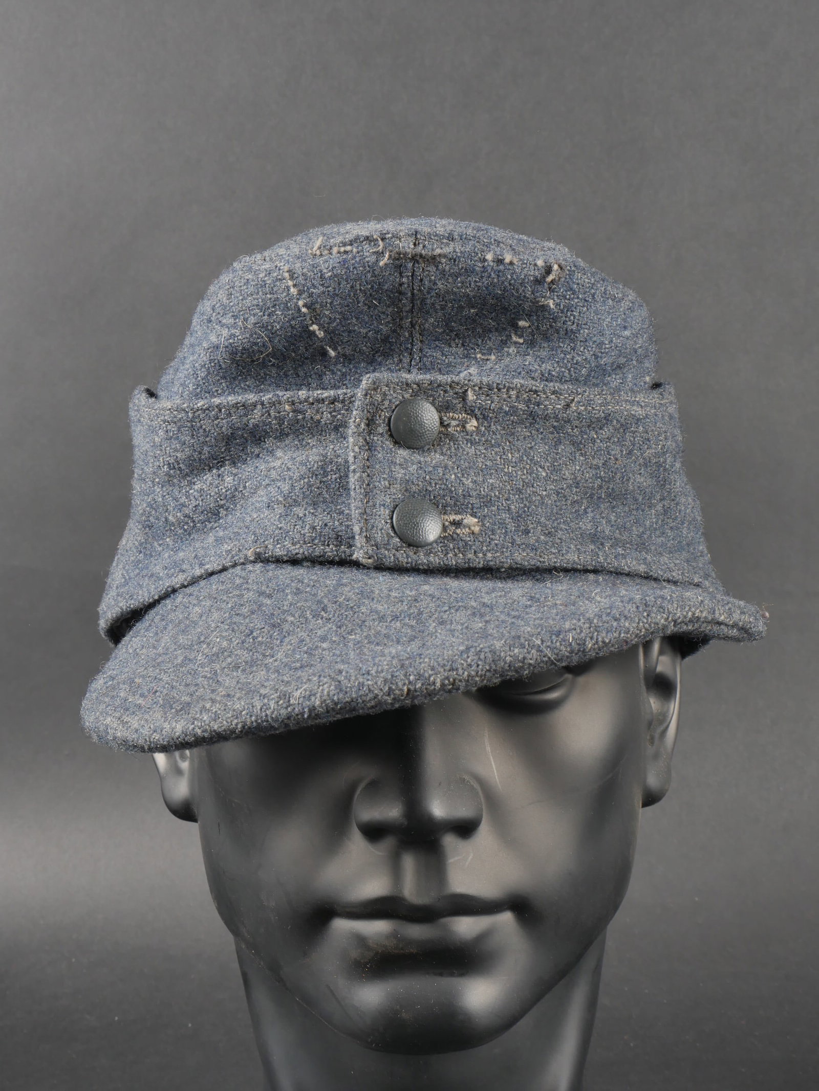 Casquette M-43 LW. Luftwaffe cap.: Casquette M-43 de la Luftwaffe. En drap gris/bleu. Deux boutons greneles bleu fermant le rabat. Le boutons sont en couleur d origine. Les insignes ont ete decousu et sont manquants. Visiere en bon eta