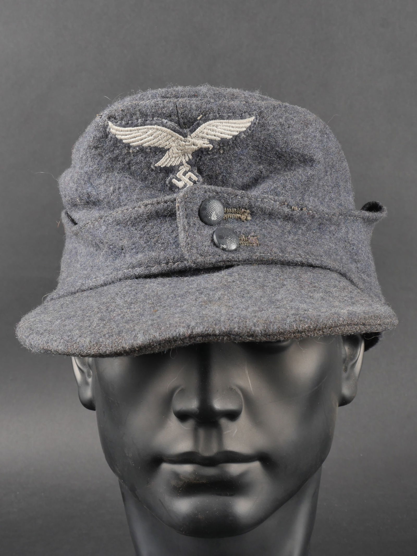 Casquette M-43 LW. Luftwaffe cap.: Casquette M-43 de la Luftwaffe. En drap gris/bleu. Deux boutons greneles bleu fermant le rabat. Le boutons sont en couleur d origine. Les insignes sont brodes et cousus main. Visiere en bon etat, mais
