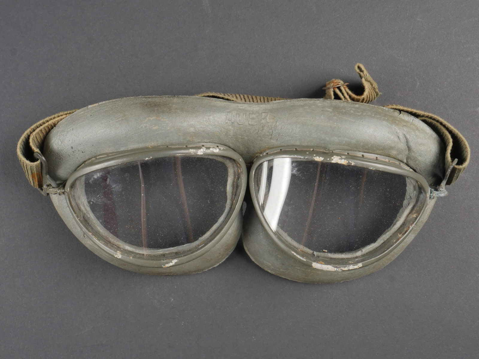 Lunette de vol Auer. German pilot glasses.: Lunettes de vol Auer. Armature en metal, couleur grise a 80%. Verres blanc. Coussin en epais caoutchouc gris. Elastique complet et souple, partiellement decolore par le soleil. Fabrication Auer. A not