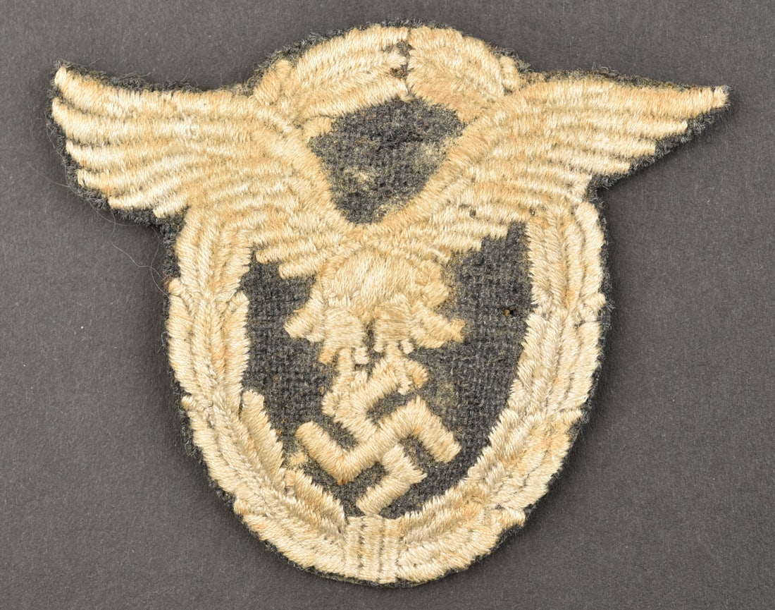 Badge de pilote LW. LW pilot badge.: Badge de pilote de la Luftwaffe. Modele en tissu bombe. Dos de la piece double en papier noir, traces de colle au dos. A noter une certaine usure et patine de la piece. Etat II+. Luftwaffe pilot badge