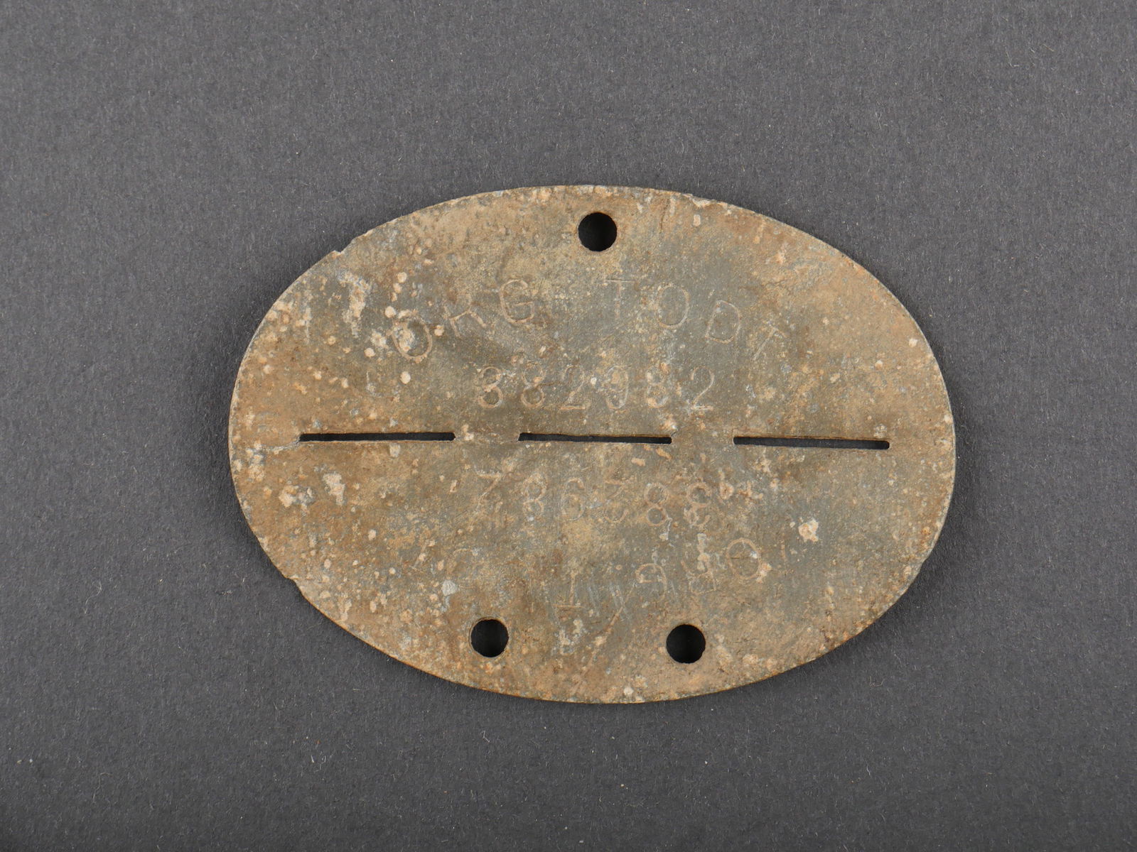 Plaque identite Organisation Todt. Org Todt dog tag.: Plaque d identite de l Organisation Todt. En metal, fortement oxydee et deformee. Marquages Org Todt 382982. A noter une certaine usure et oxydation de la piece. Etat II+. Identity Tag of the Organisa