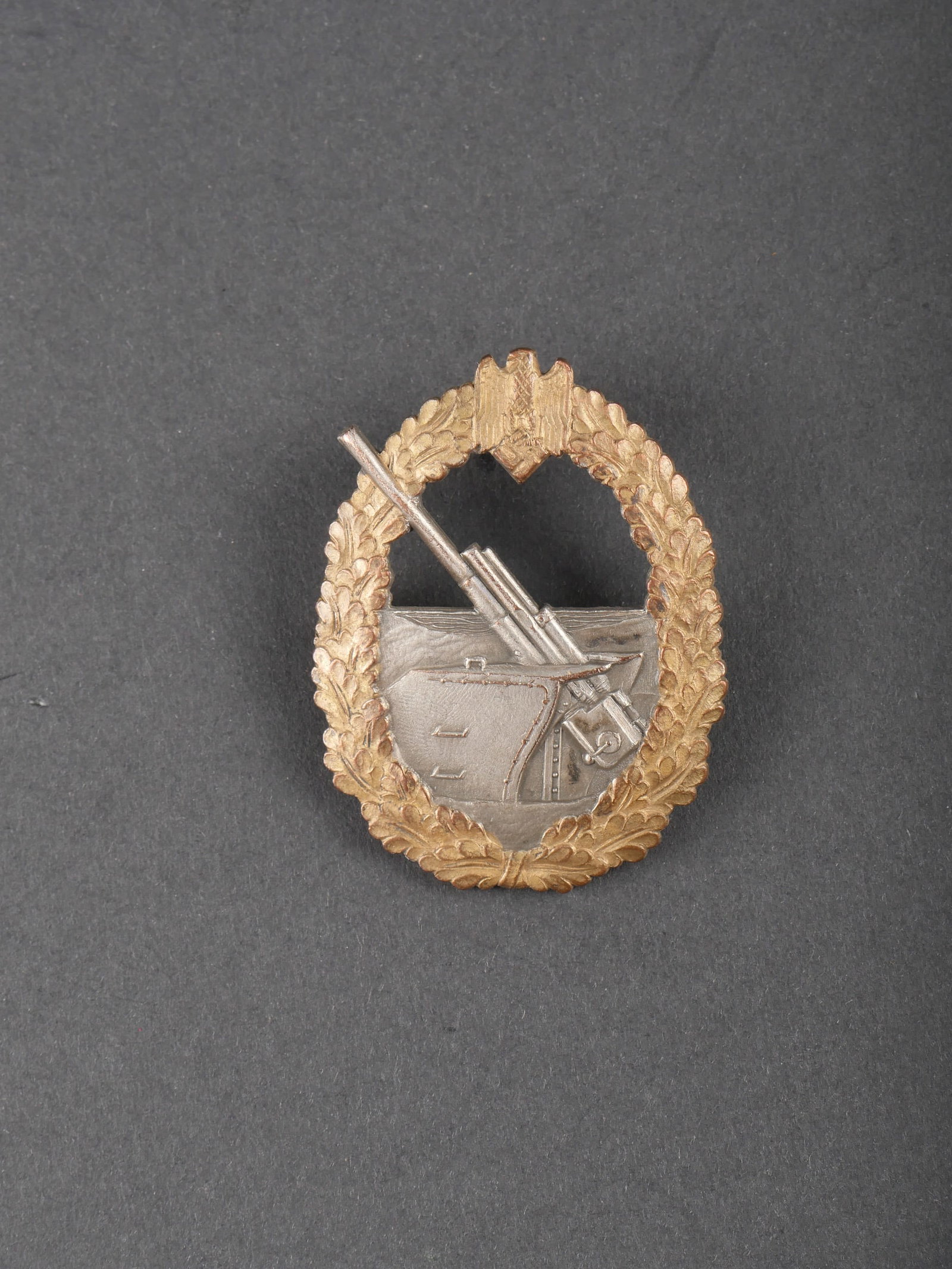 Insigne de l artillerie cotiere. Kriegsmarine insignia.: Insigne de l artillerie cotiere. Dorure et argenture a 90%. Petit crochet absent. Attache horizontale. Fabrication Bacqueville. A noter une certaine usure et patine de la piece. Etat II+. Coastal arti