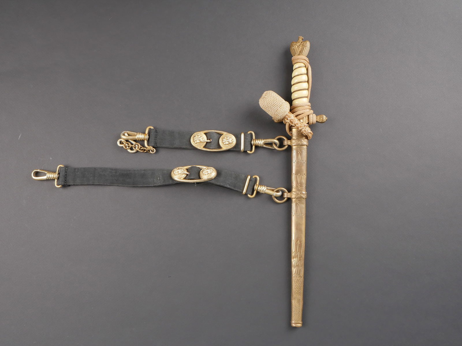 Dague officier Kriegsmarine. Kriegsmarine dagger.: Dague d officier de la Kriegsmarine. Garniture en metal dore. Poignee en celluloid blanche, quelques fissures visibles. Dragonne complete, nouee de maniere non reglementaire. Bouton poussoir fonctionn