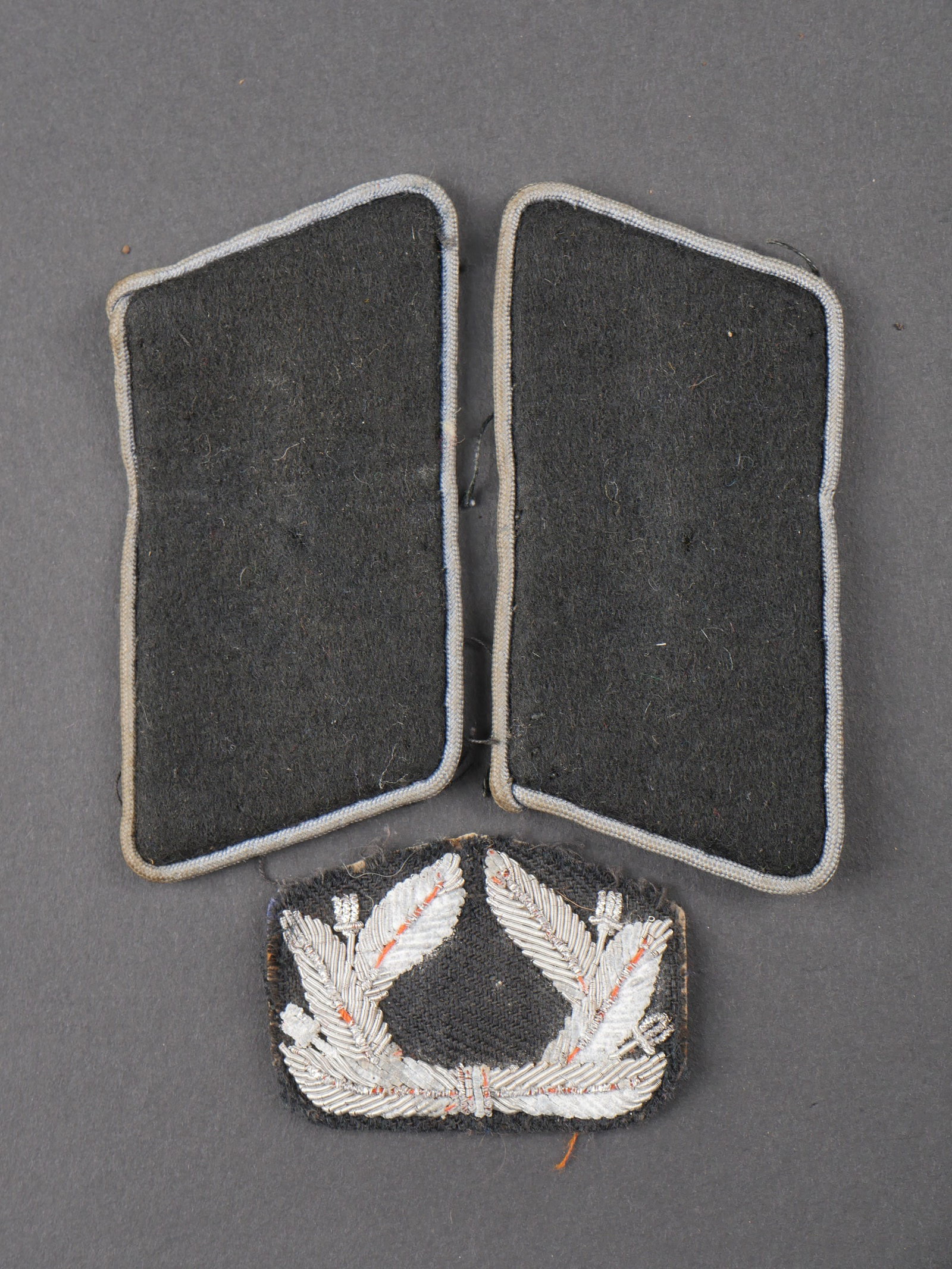 Insignes hollandais. Dutch insignia.: Insignes hollandais. Comprenant une cocarde en cannetille sur fond noir du VNV flamand. Une paire de coins de col en drap noir, lisere gris. A noter une certaine usure et patine des pieces. Etat II+. 