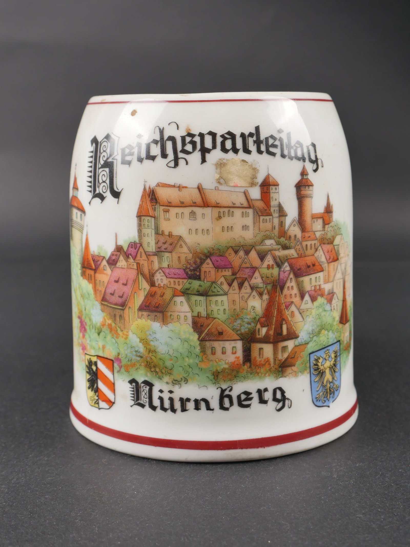 Chope Reichsparteitag Nurnberg. Reichsparteitag mug.: Chope Reichsparteitag Nurnberg. En porcelaine blanche, decors en couleur, bien marque Reichsparteitag Nurnberg. Anse complete. Couvercle manquant. Quelques fissures visibles. A noter une certaine usur