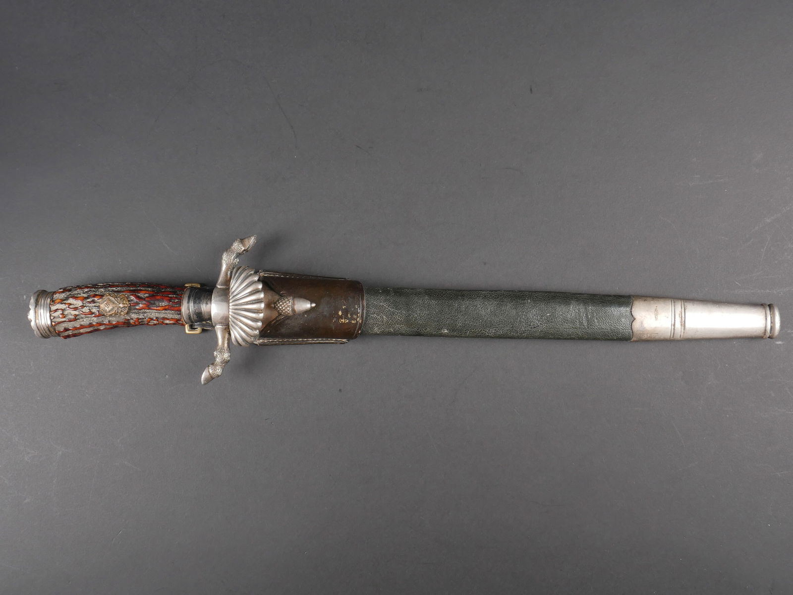 Dague de chasse. German Hunting Dagger.: Dague de la federation des chasseurs allemand. Pommeau en metal couleur argent. Poignee en imitation bois de cerf. Insignes des Reichsbund Deutsche Jagerschaft. Garde en S, a decors de sabots de cervi