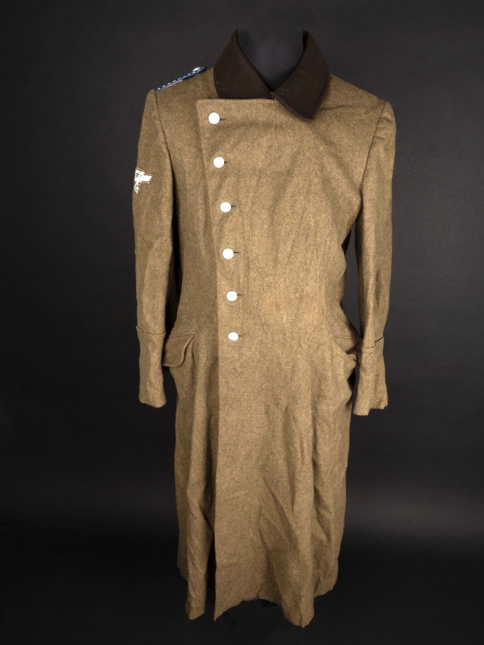 Manteau NSKK. NSKK mantel.: Manteau NSKK. En drap kaki. Col en drap marron. Tous les boutons sont presents. Aigle de manche NSKK en tissu tisse argente. Visiblement monte a la machine a coudre. Patte d epaule au grade d Obertrup
